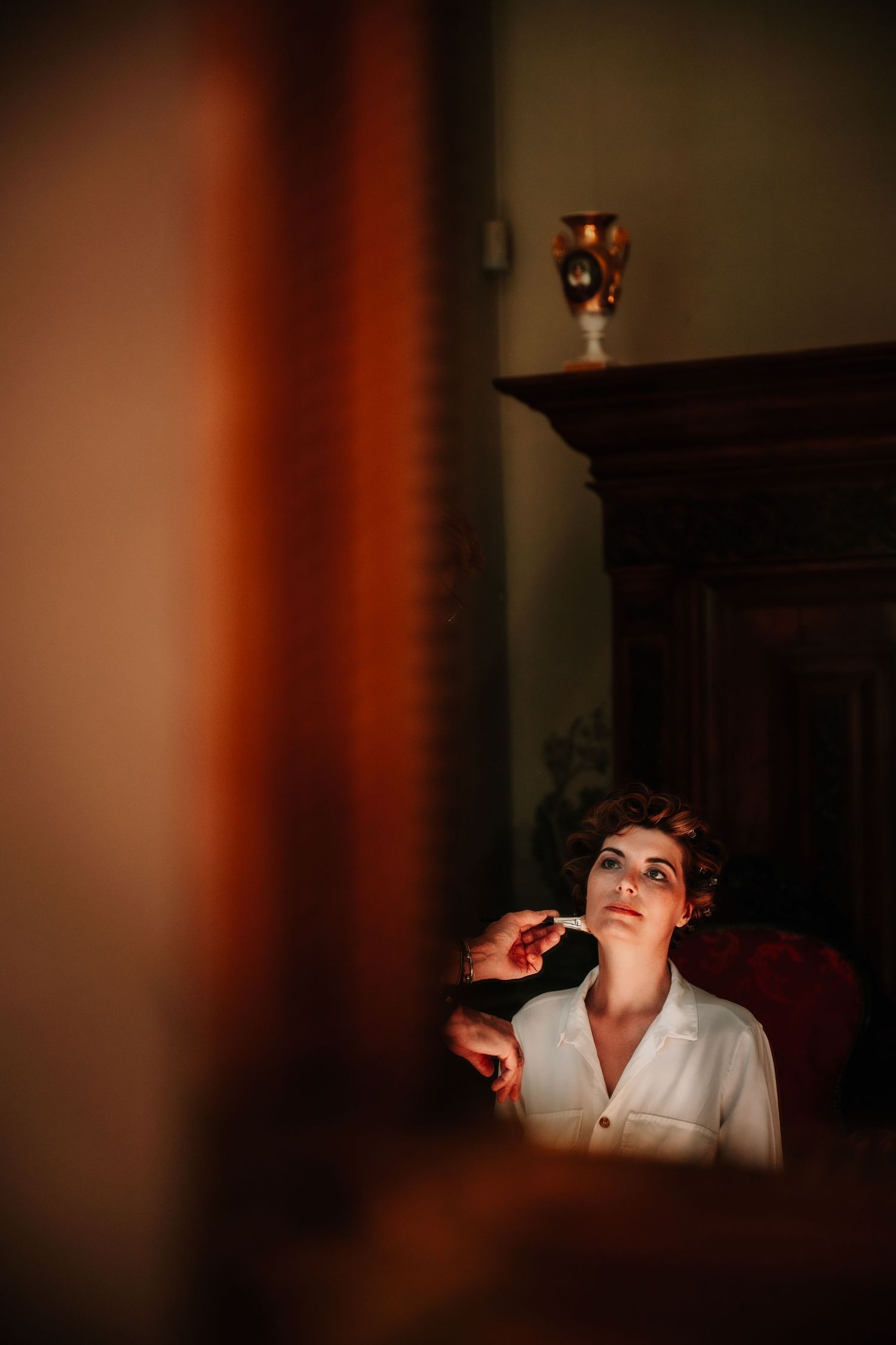 Dramatic low-key lighting illuminates a person in white against a dark background creating a moody atmosphere.