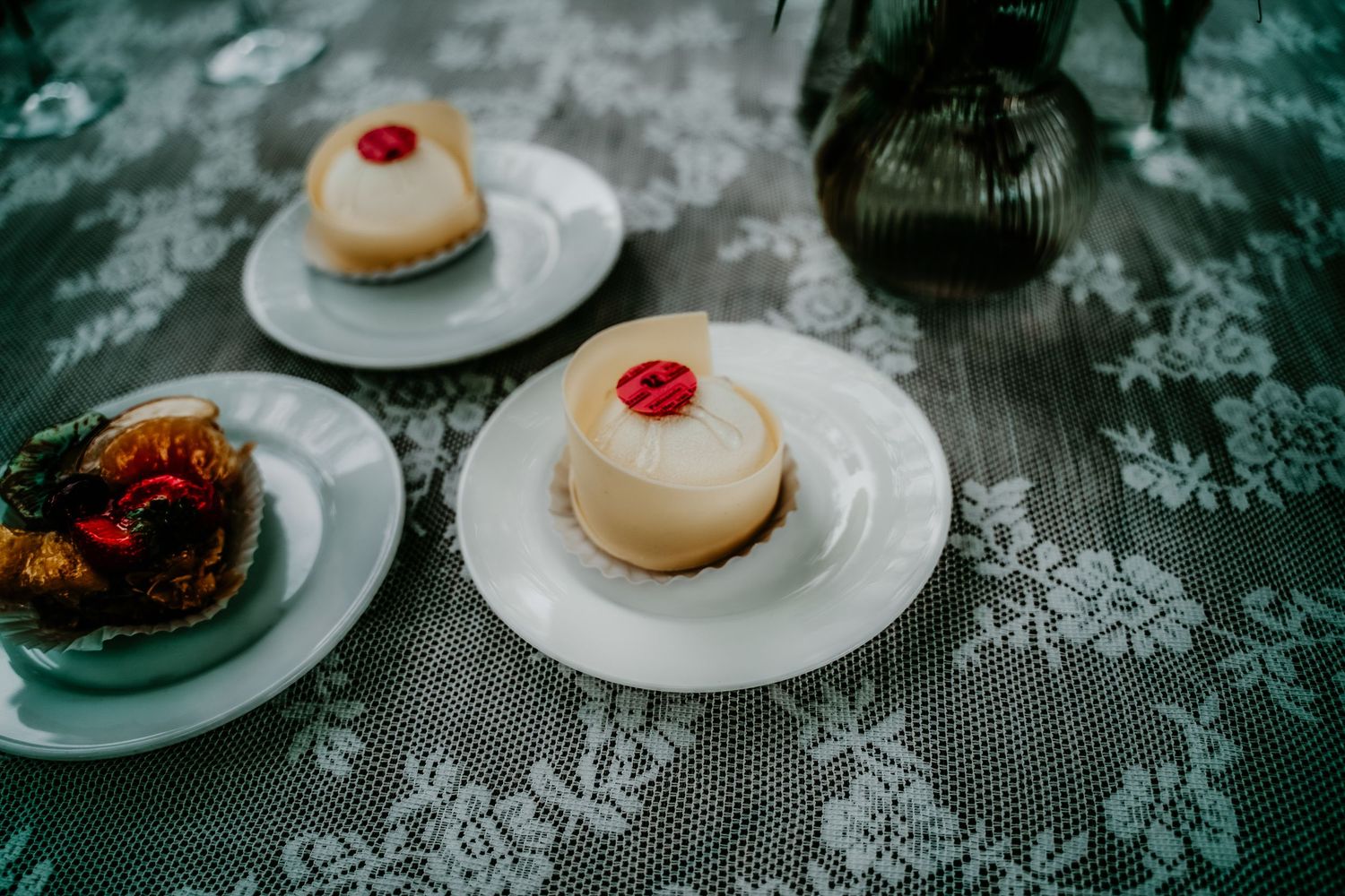 A collage of dessert plates featuring donuts with cherries and other sweet treats on a dark lace tablecloth.
