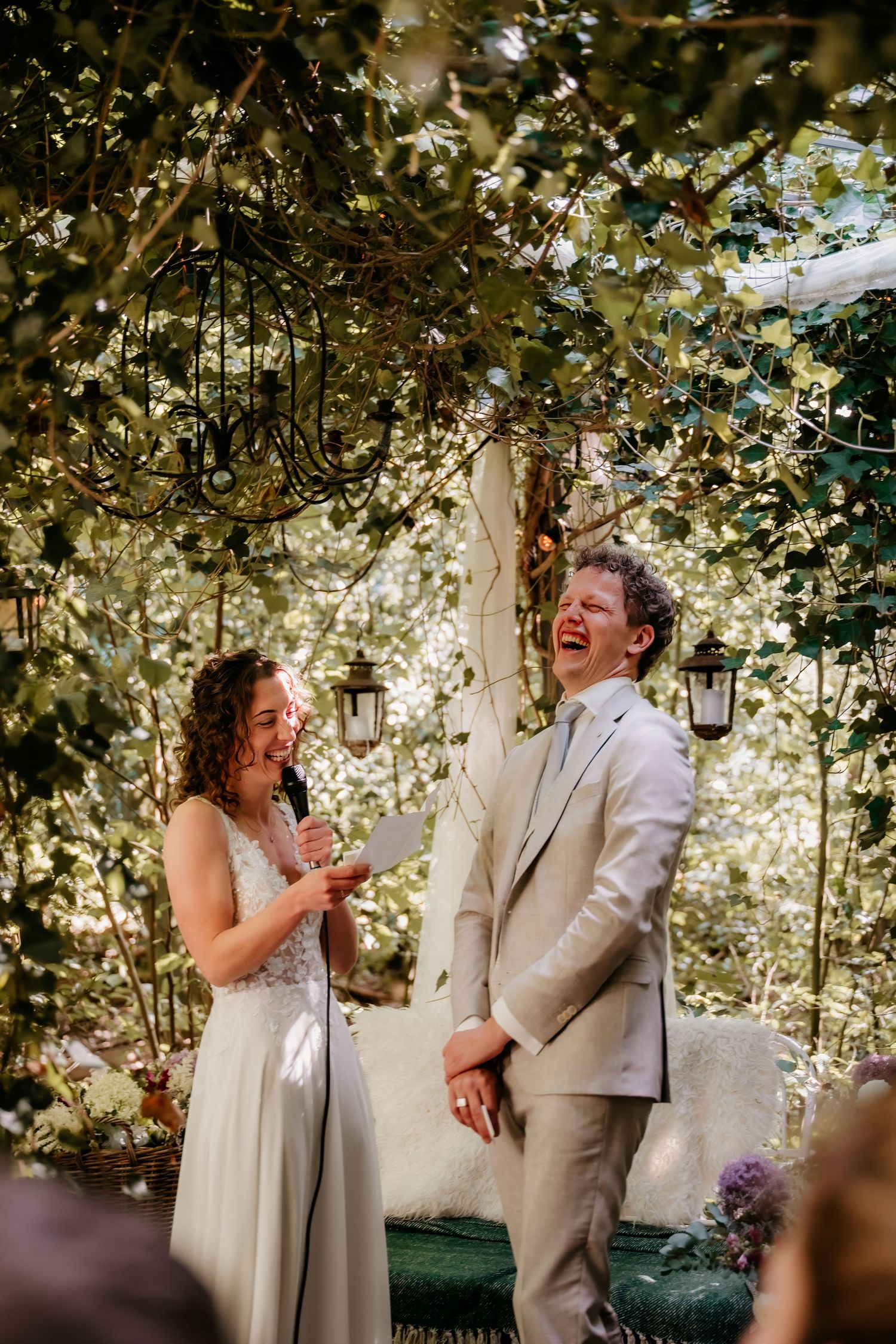 Joyful couple shares a candid laughing moment during their outdoor garden wedding ceremony.