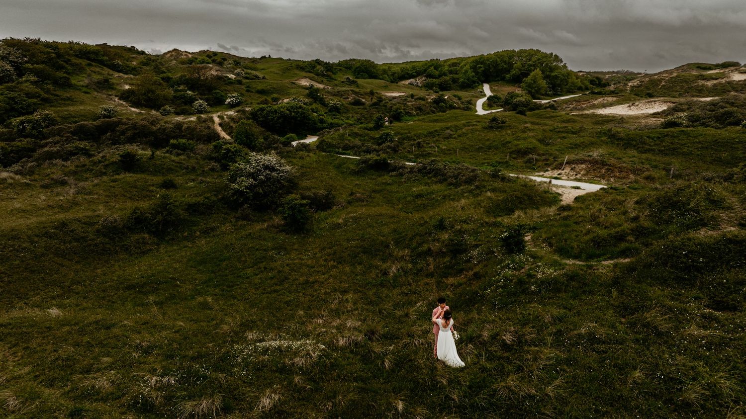 A panoramic view of a rugged coastal landscape with green hills and dramatic cloudy skies.