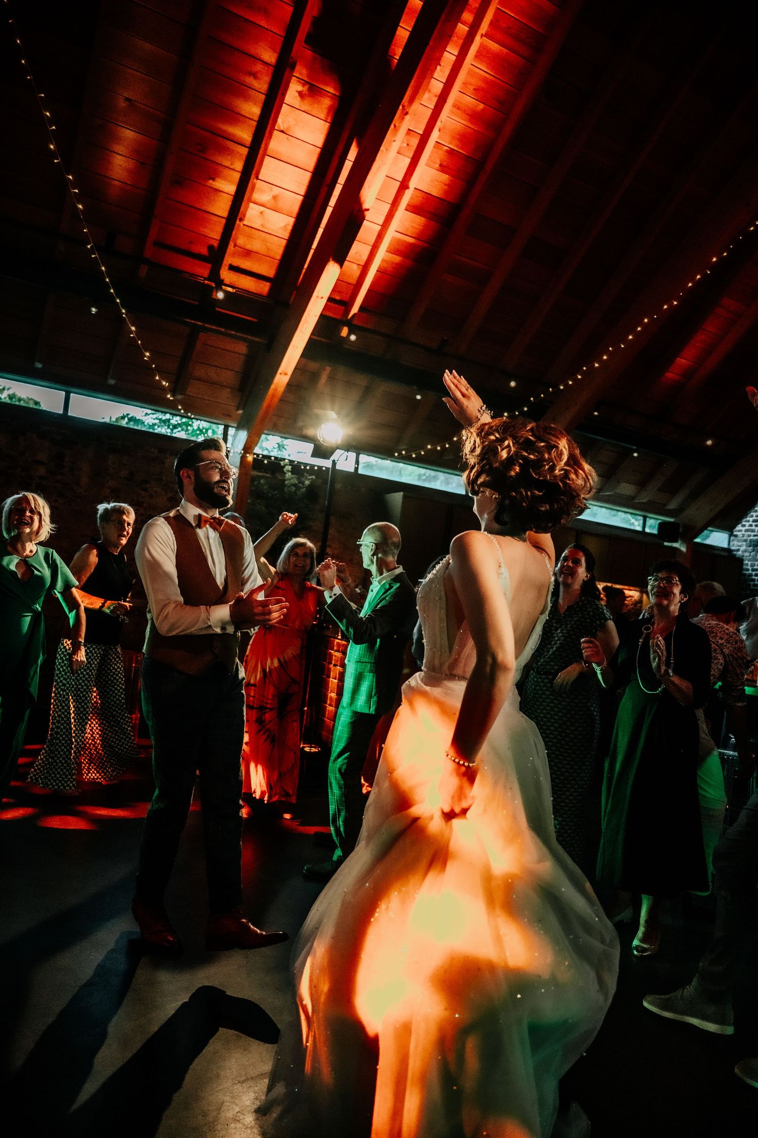A dimly lit reception venue with string lights and dancing silhouettes.
