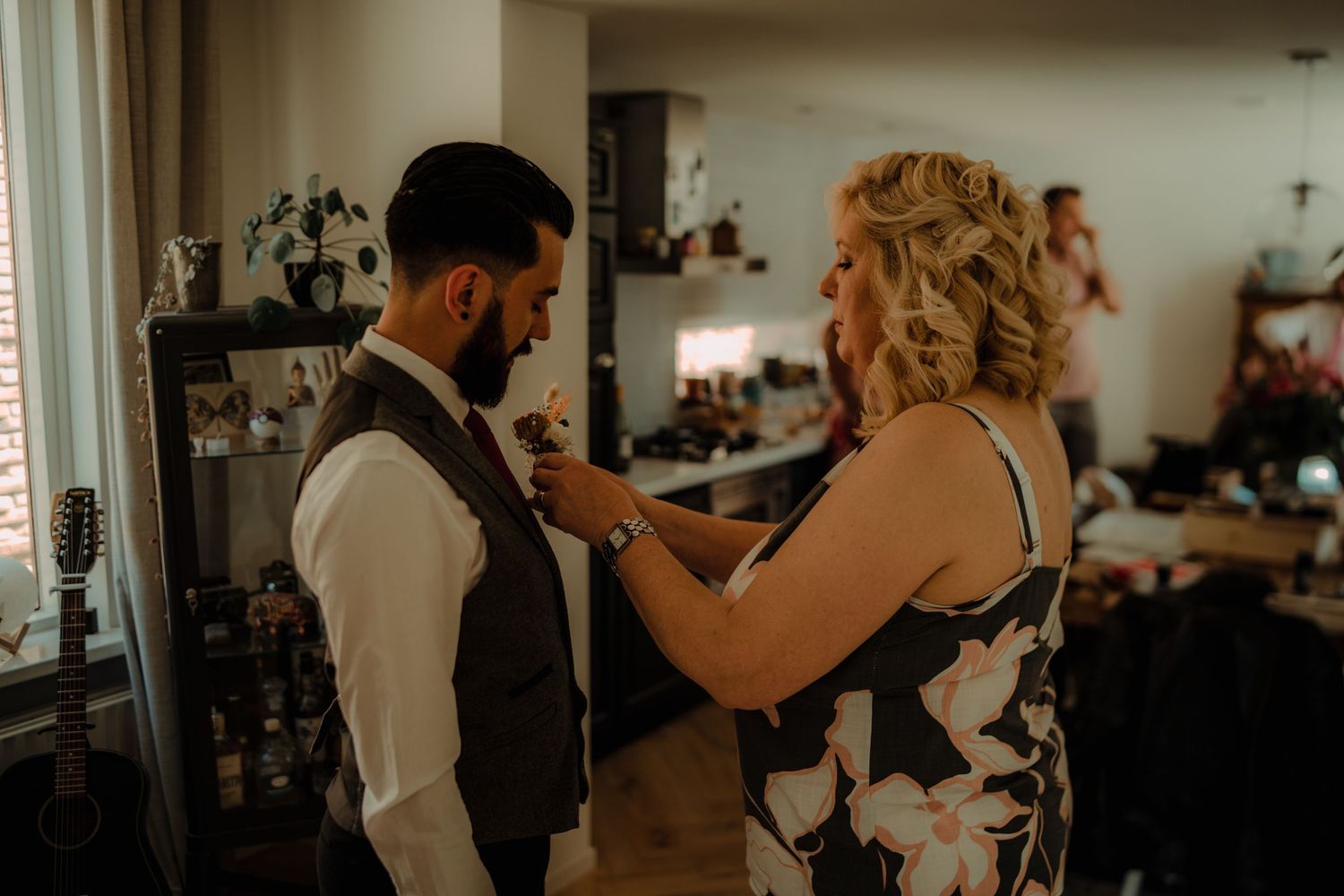 A wedding preparation scene shows final adjustments being made to formal attire in a warmly lit room.
