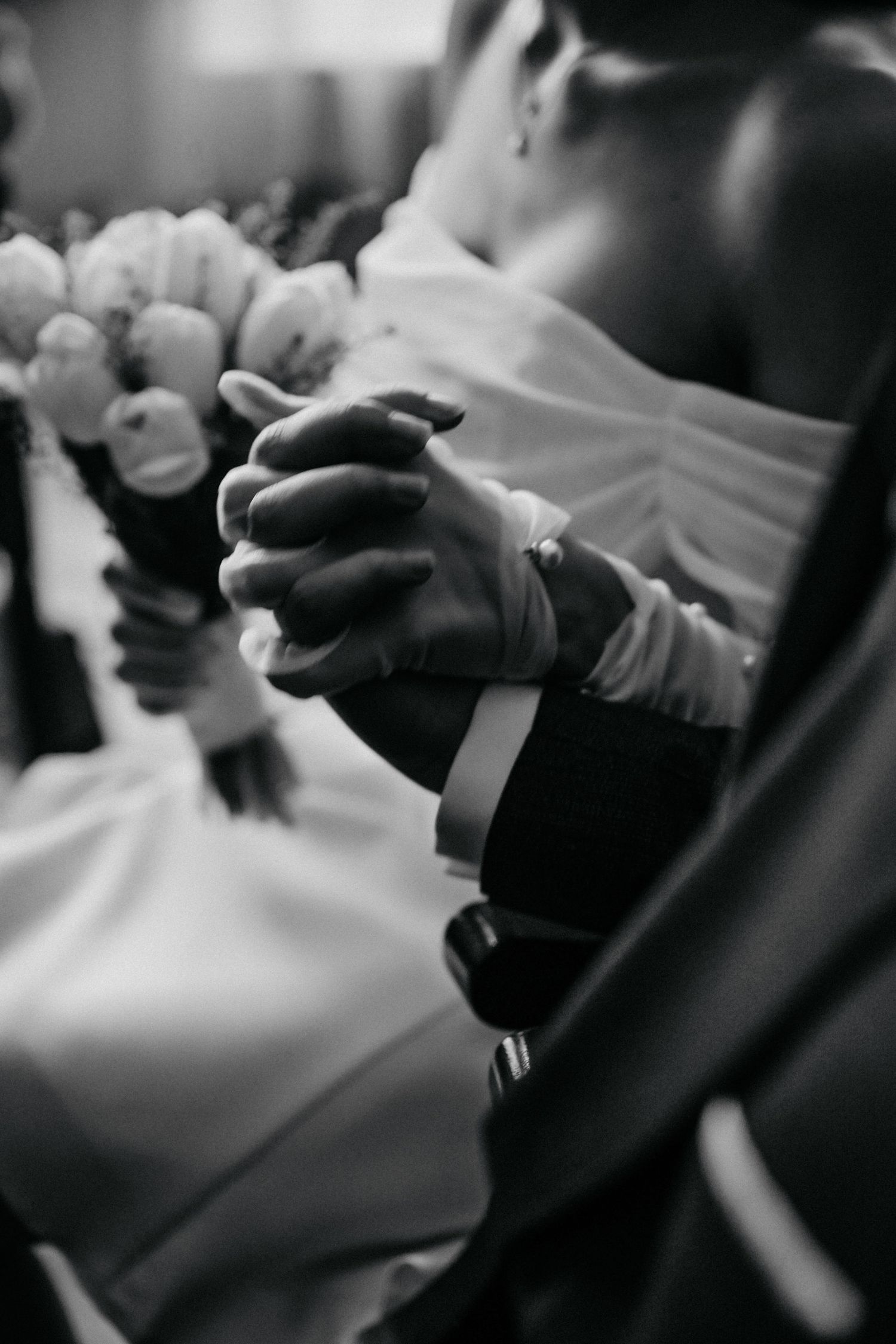 Close-up black and white photo of clasped hands during wedding ceremony.