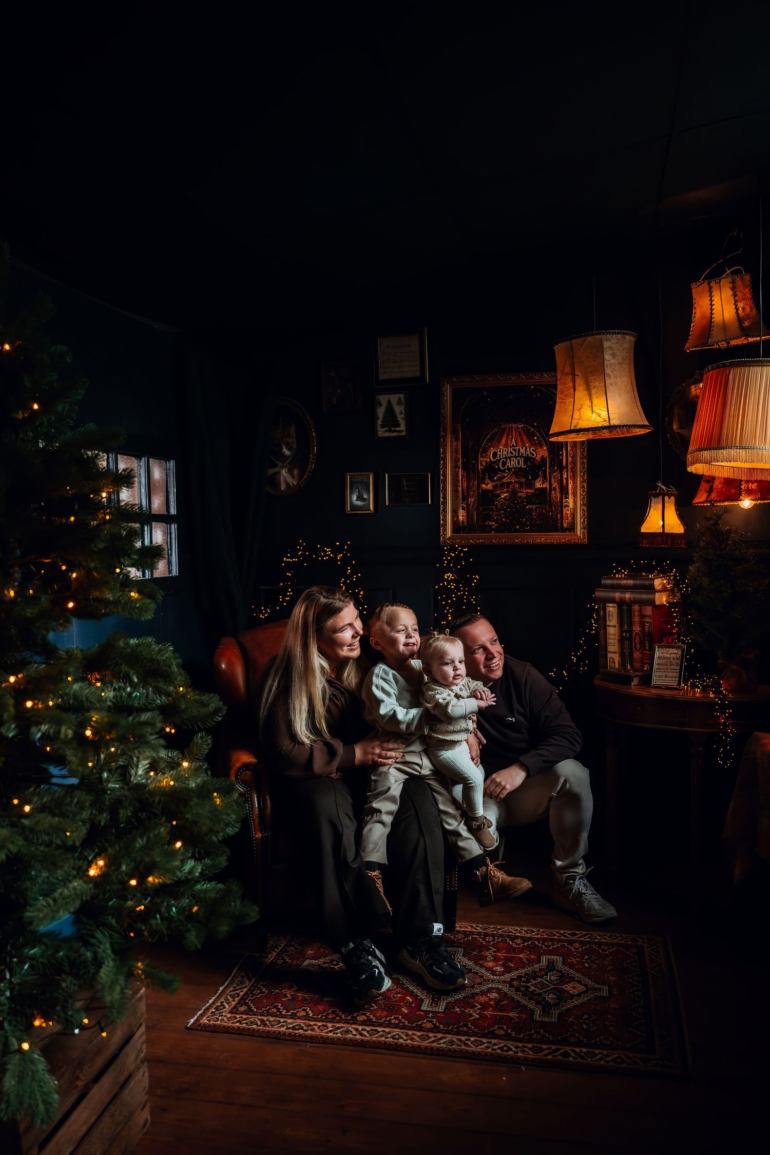 A warm family Christmas scene with decorated tree, glowing lamps, and cozy seating in a dark living room.