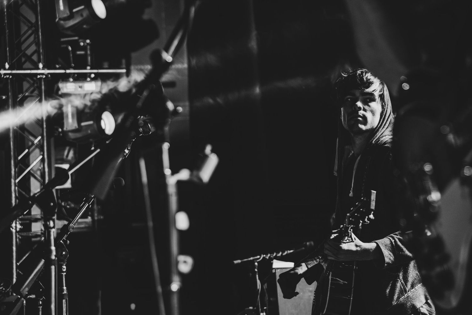 Black and white concert performance photo showing musicians on stage with dramatic lighting and silhouettes.