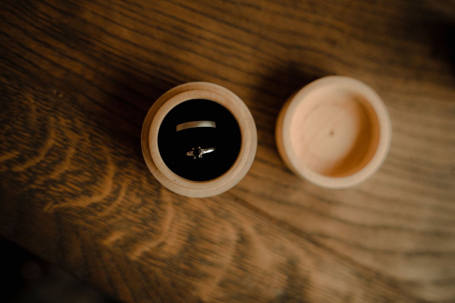 Two coffee cups on a wooden surface, one black and one light colored, viewed from above.