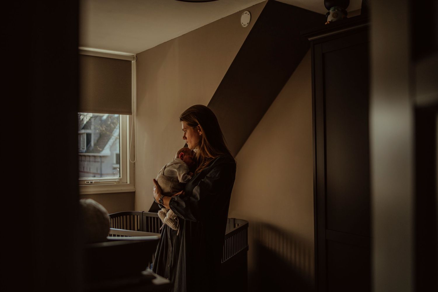Silhouette by a window shows a tender moment of comfort and care.