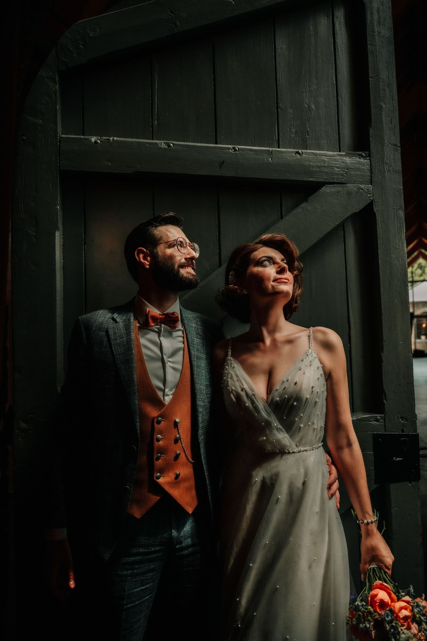 A dramatic indoor portrait with moody lighting against dark wooden walls.