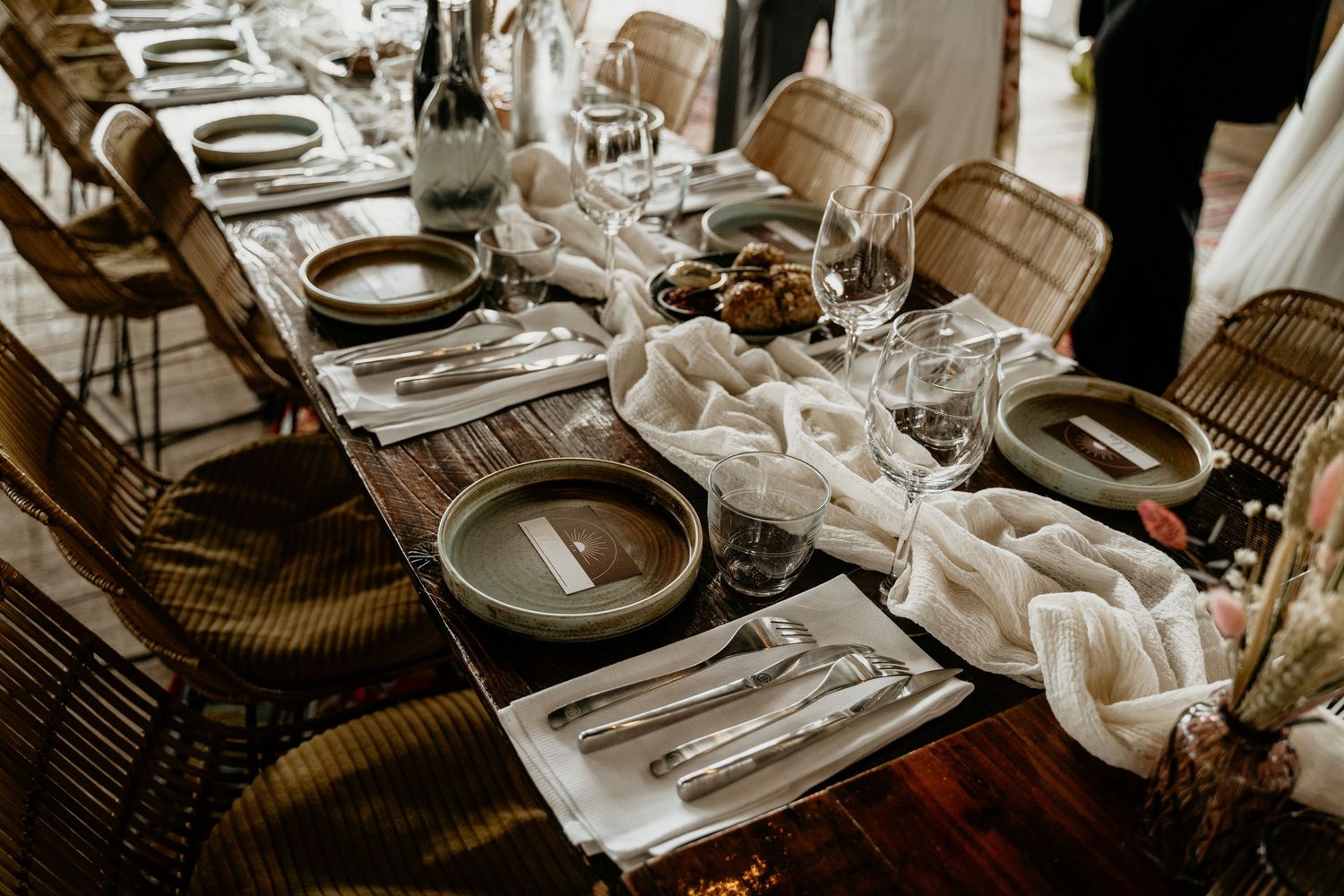 A rustic wedding table setting with white linens and elegant place settings on a wooden table.
