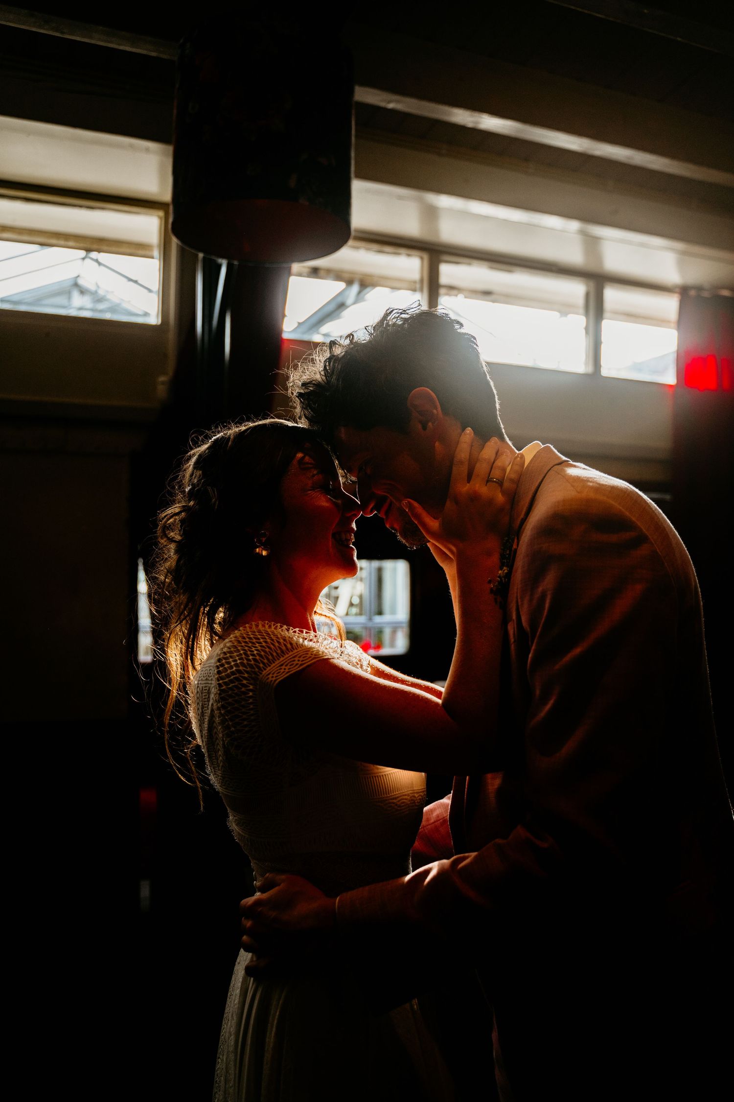 A romantic silhouette of a couple sharing an intimate moment in warm sunlit room.