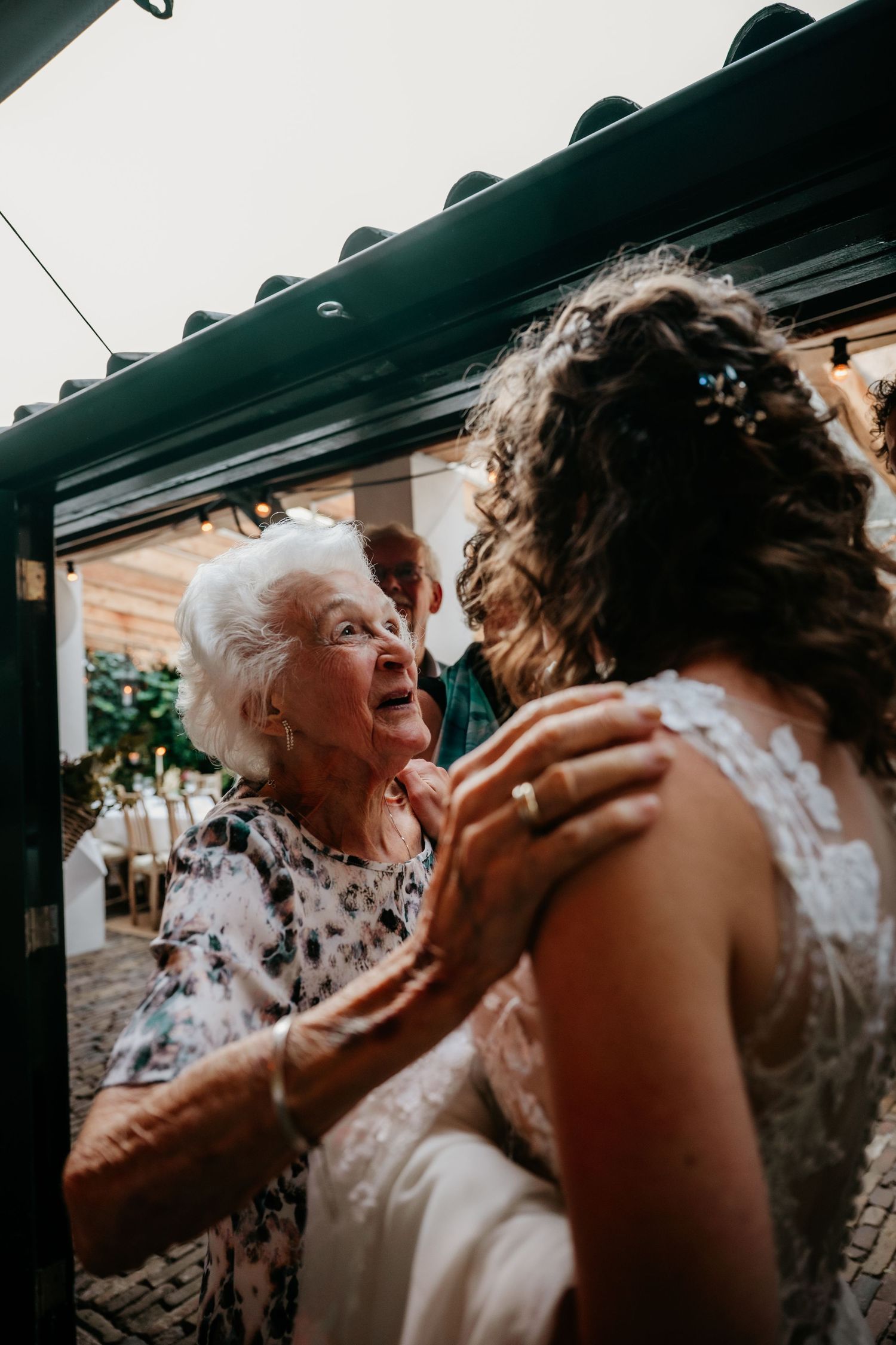 Two wedding attendees share a joyful, candid moment of laughter during the reception celebration.