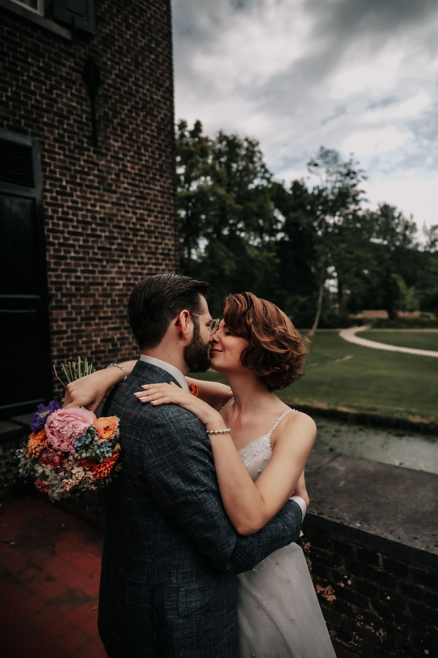 A romantic wedding couple embraces outside a brick building on their special day.