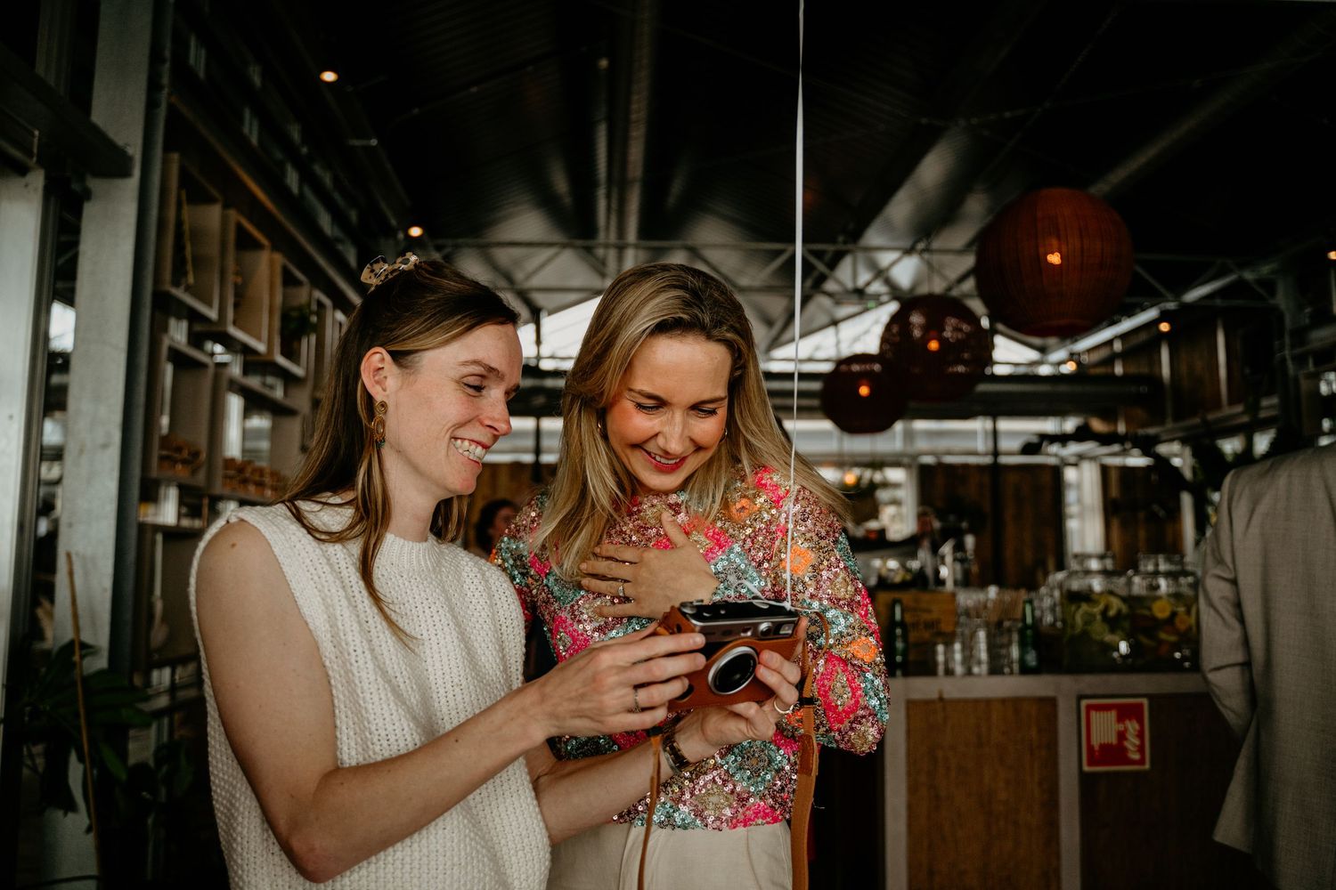 People interacting and embracing in a dimly lit indoor venue with natural window light streaming in.