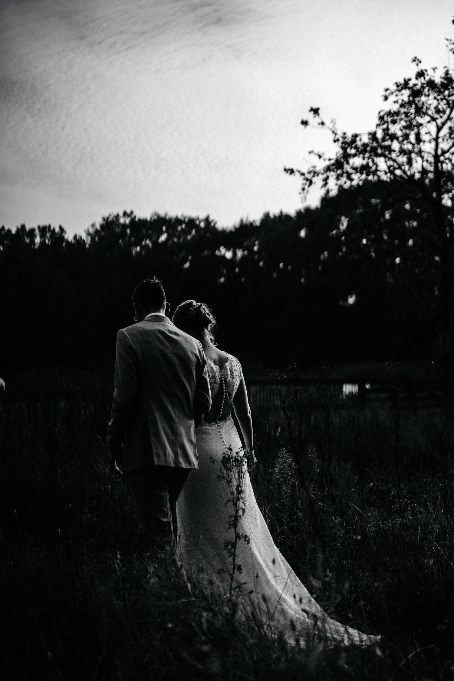 A series of dark monochromatic photos showing a ghostly figure in a white dress standing in a shadowy field at dusk.