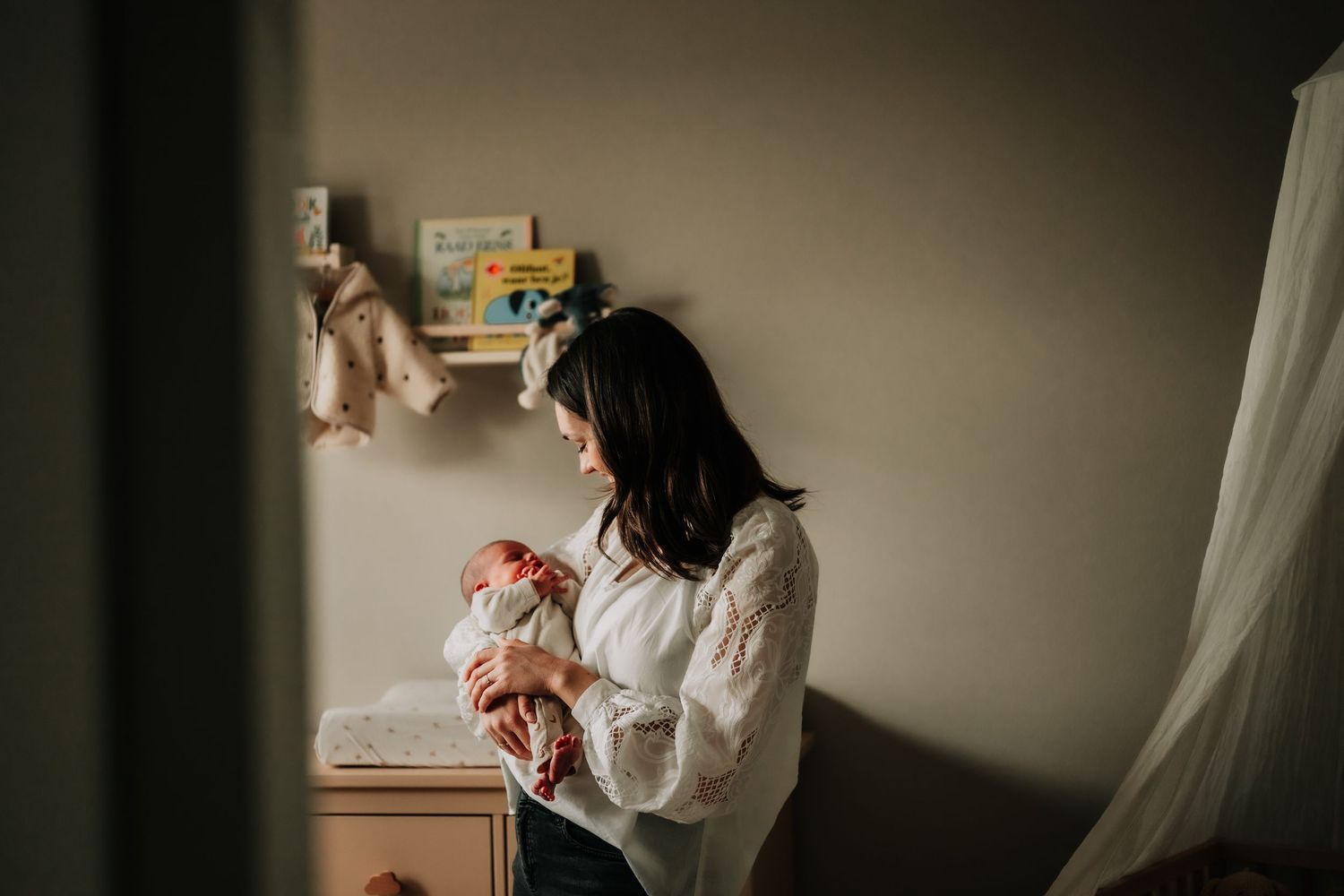 A quiet nursery moment with a changing table and white curtains.