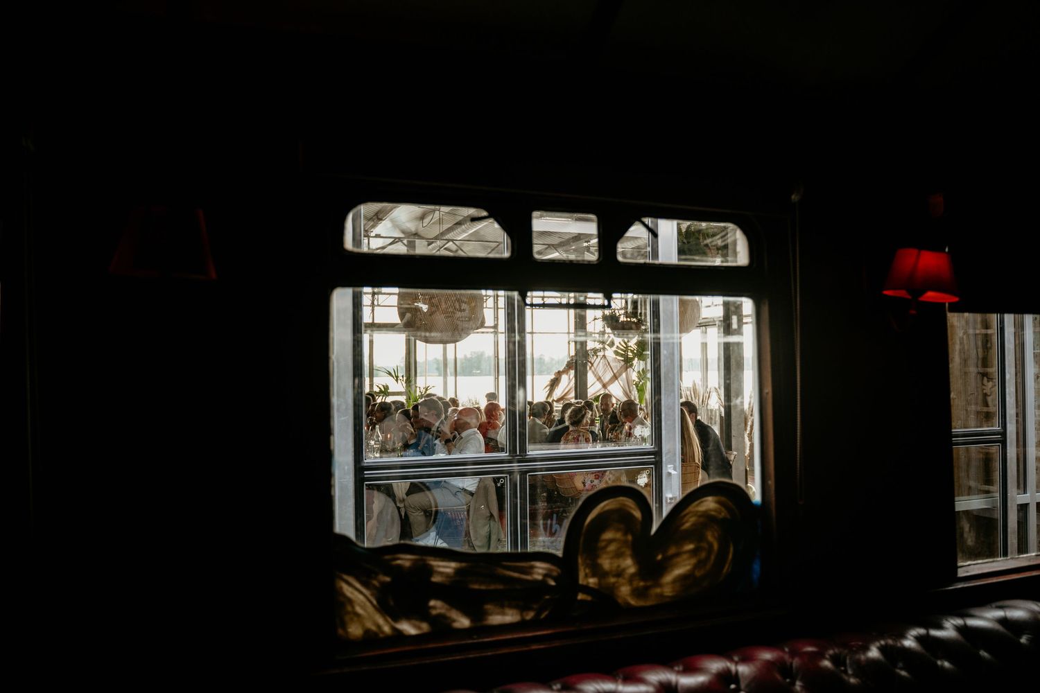 Dark silhouette view through windows of a wedding reception space.