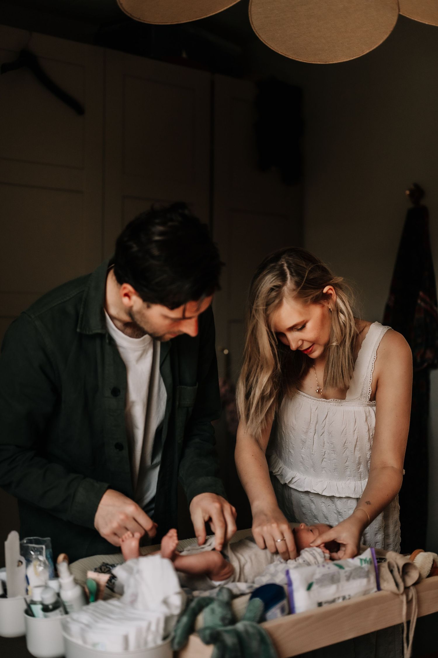 Couple working together at a table with crafting supplies in a dimly lit room.