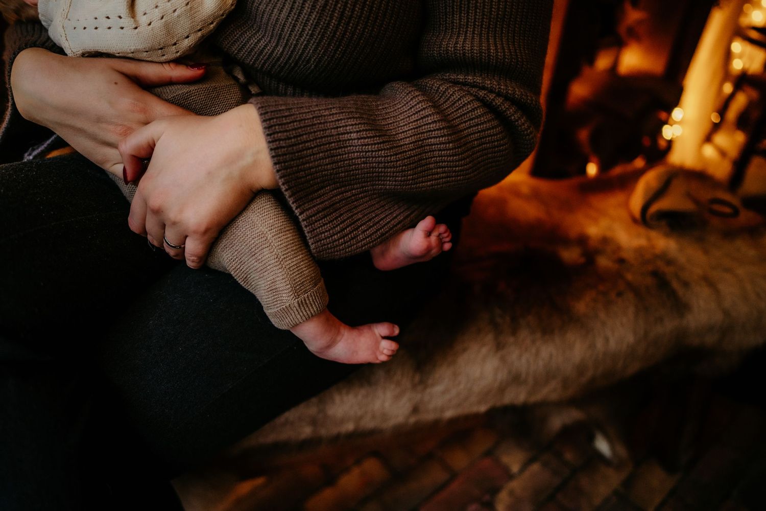 Cozy fireplace scene with tiny baby feet and warm knit clothing.