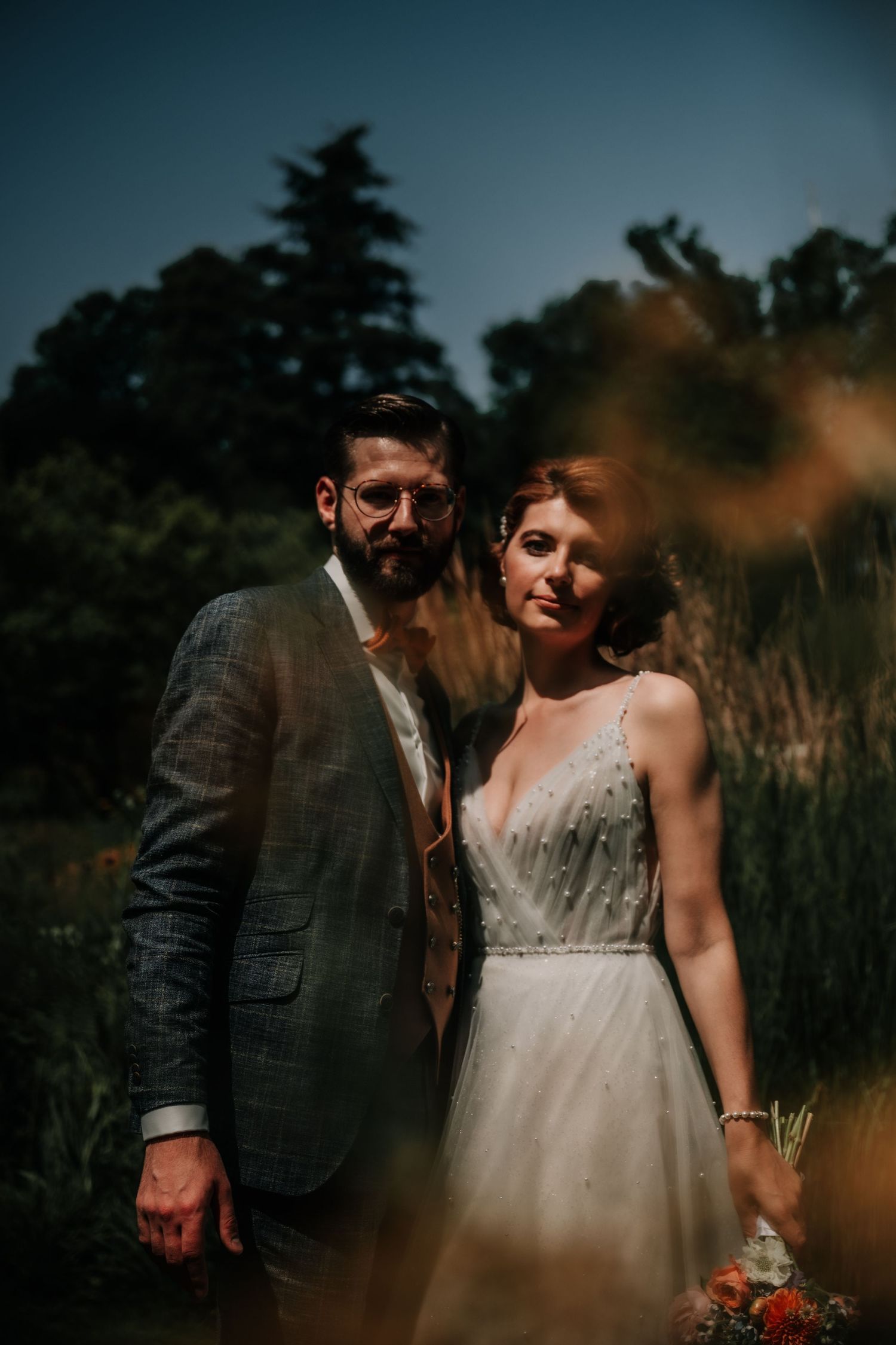 An intimate portrait session captured in a garden with dramatic evening lighting.