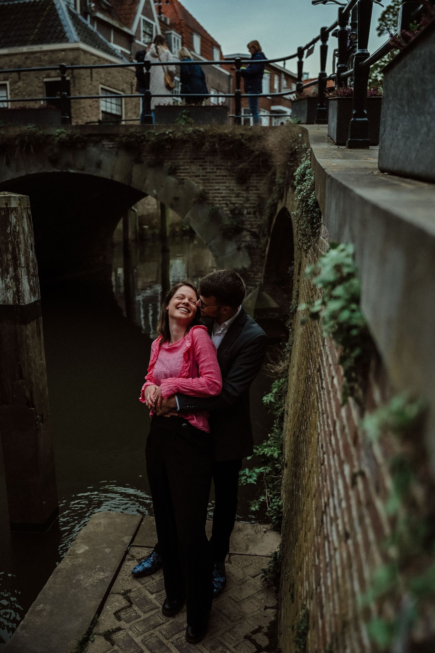 A couple stands close together in a cozy outdoor alleyway while sharing an intimate moment.
