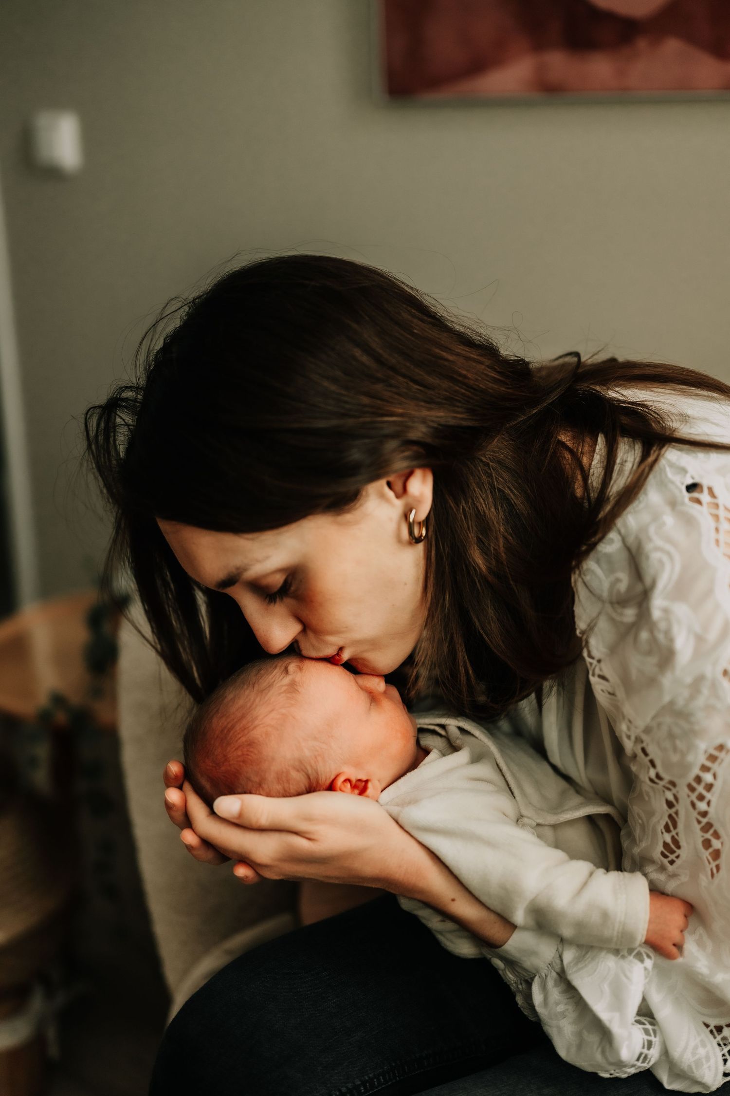 Tender moment between mother and newborn in warm natural lighting.
