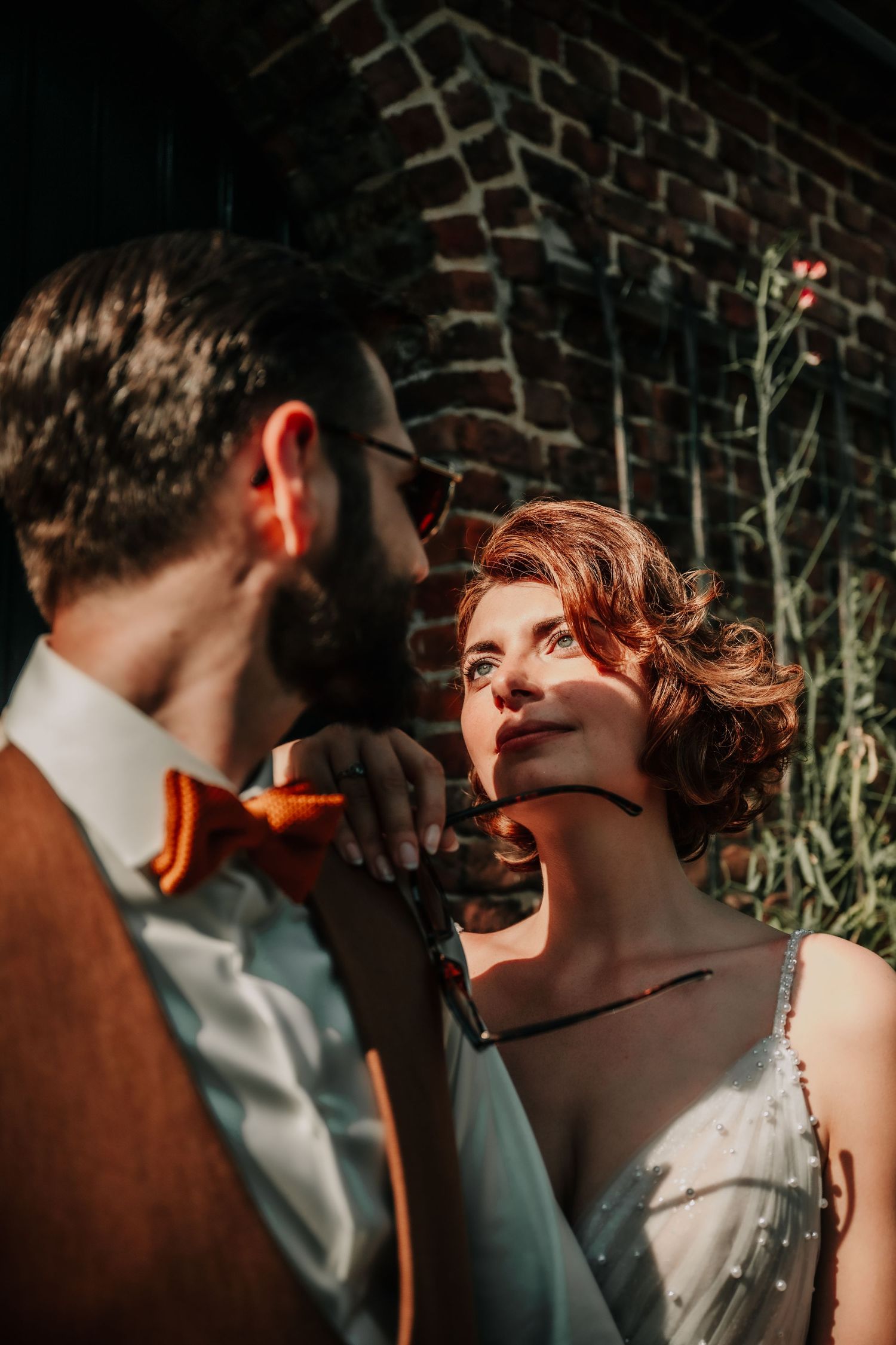 Romantic sunset portraits of newlyweds against a rustic brick wall backdrop.