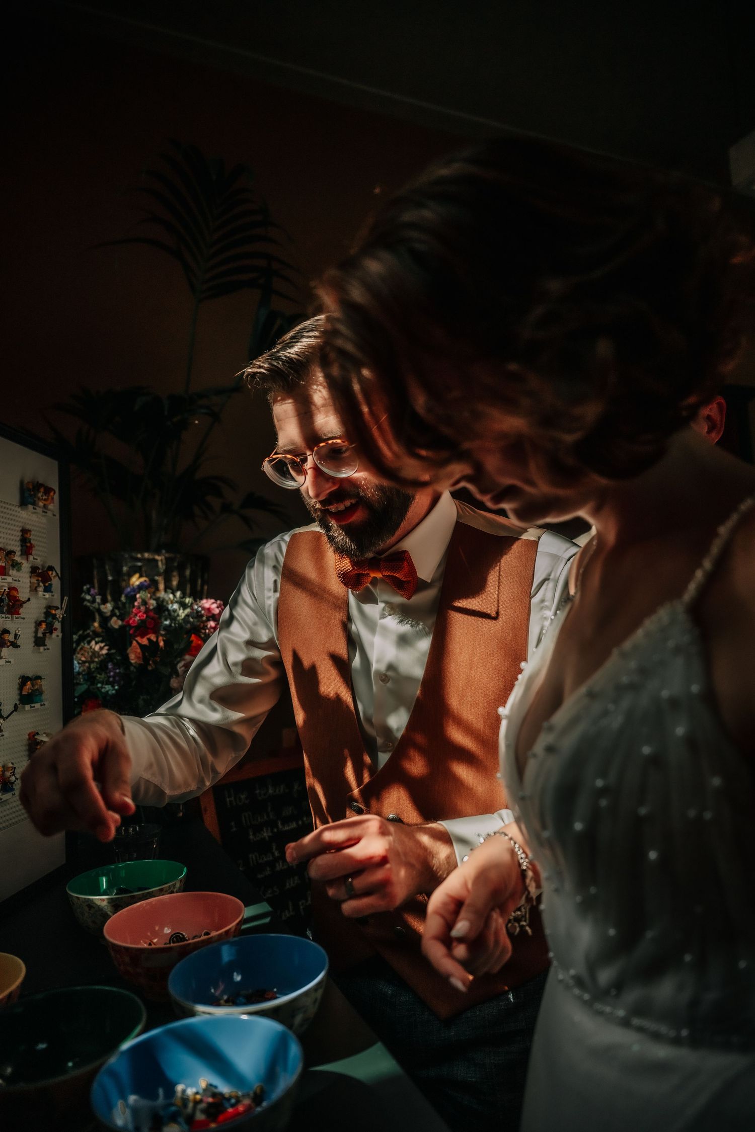 Wedding reception guests gathered around blue serving bowls in dim lighting.