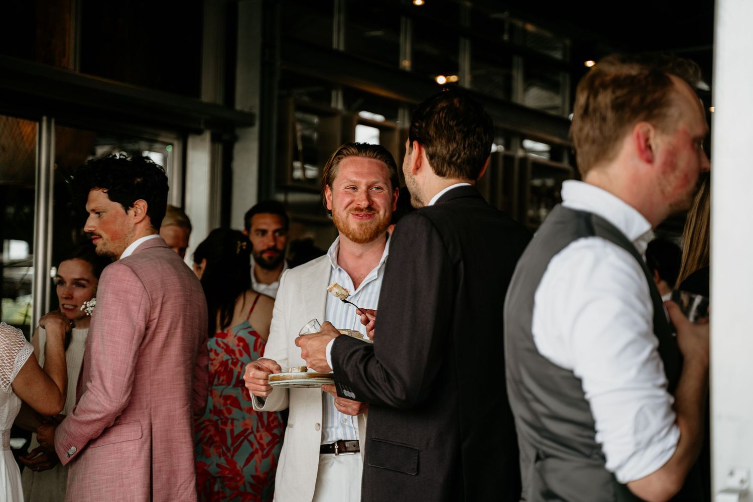 Wedding reception venue with guests mingling in casual indoor setting.