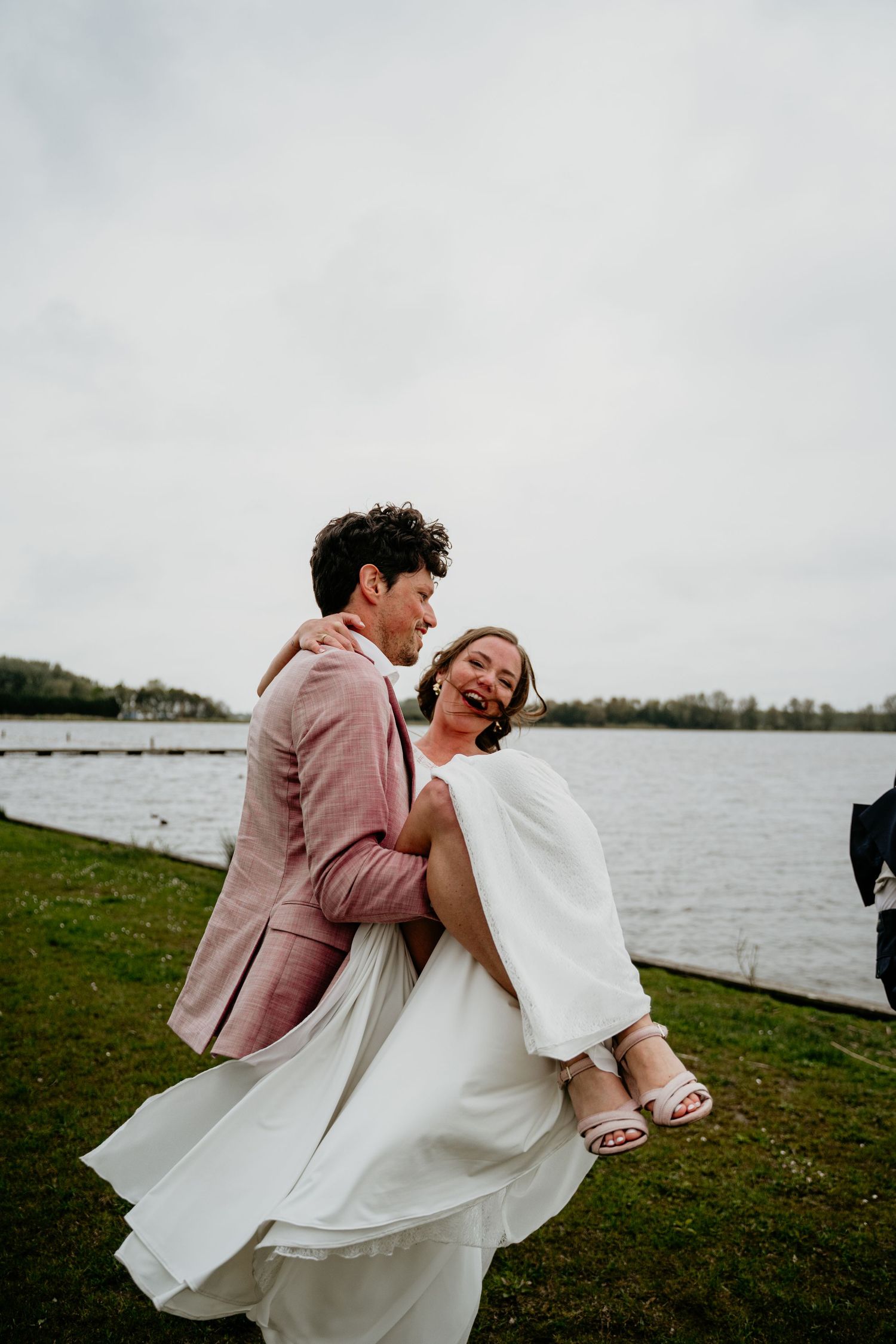 Couple shares playful moment by the waterfront with dramatic dip pose.