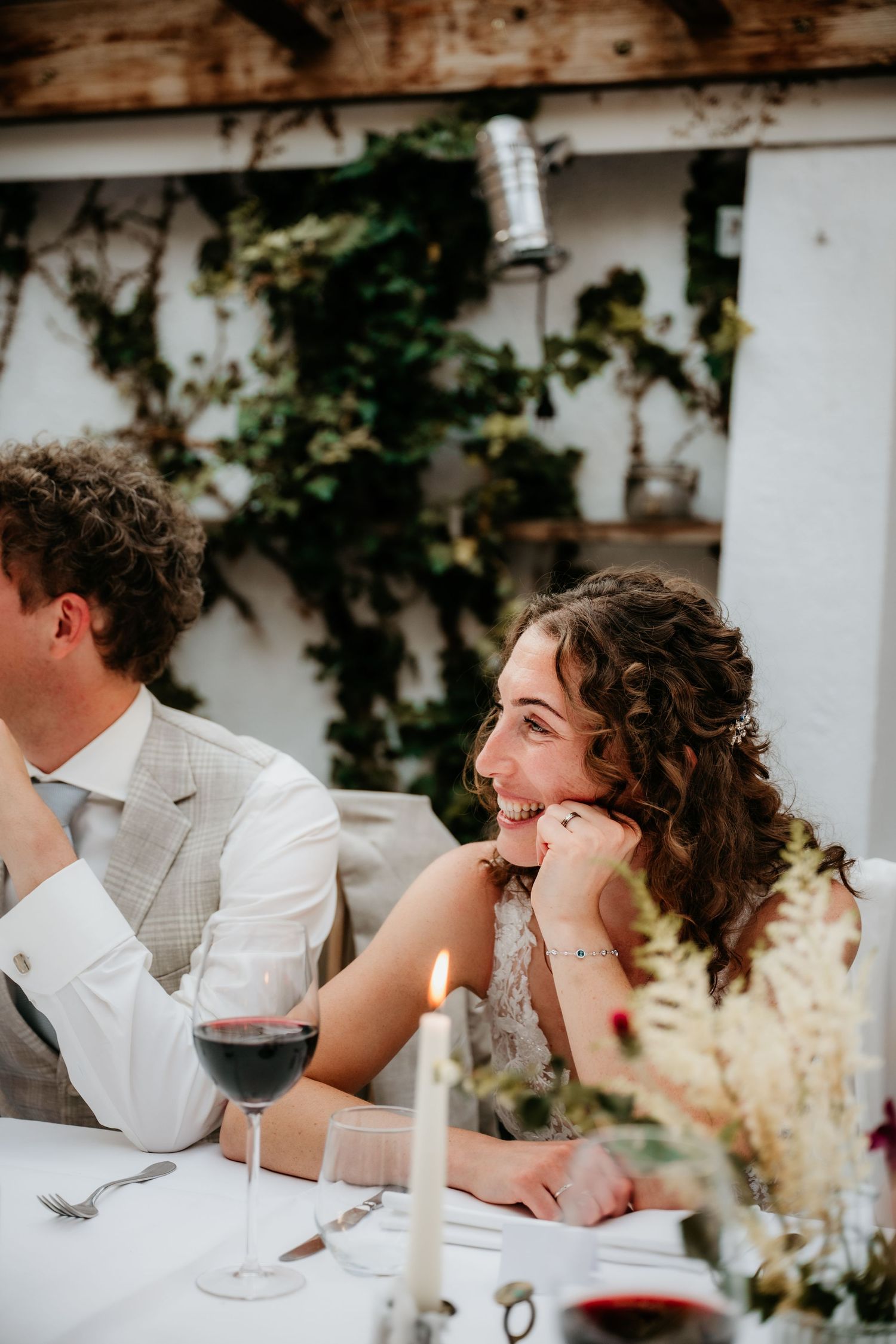 A joyful moment captured during an outdoor wedding reception with ivy-covered walls.