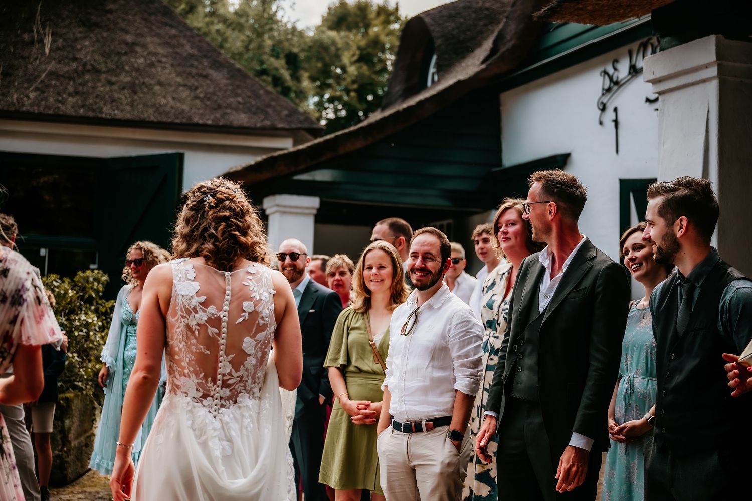 Wedding guests gather outside a rustic building during an outdoor celebration.