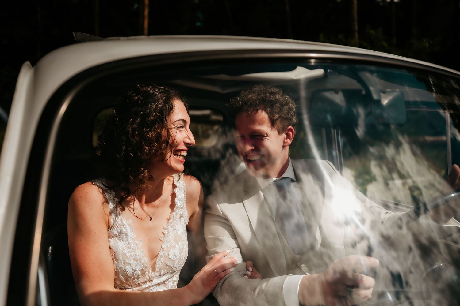 Newlyweds sharing a romantic moment in the back of a classic car.
