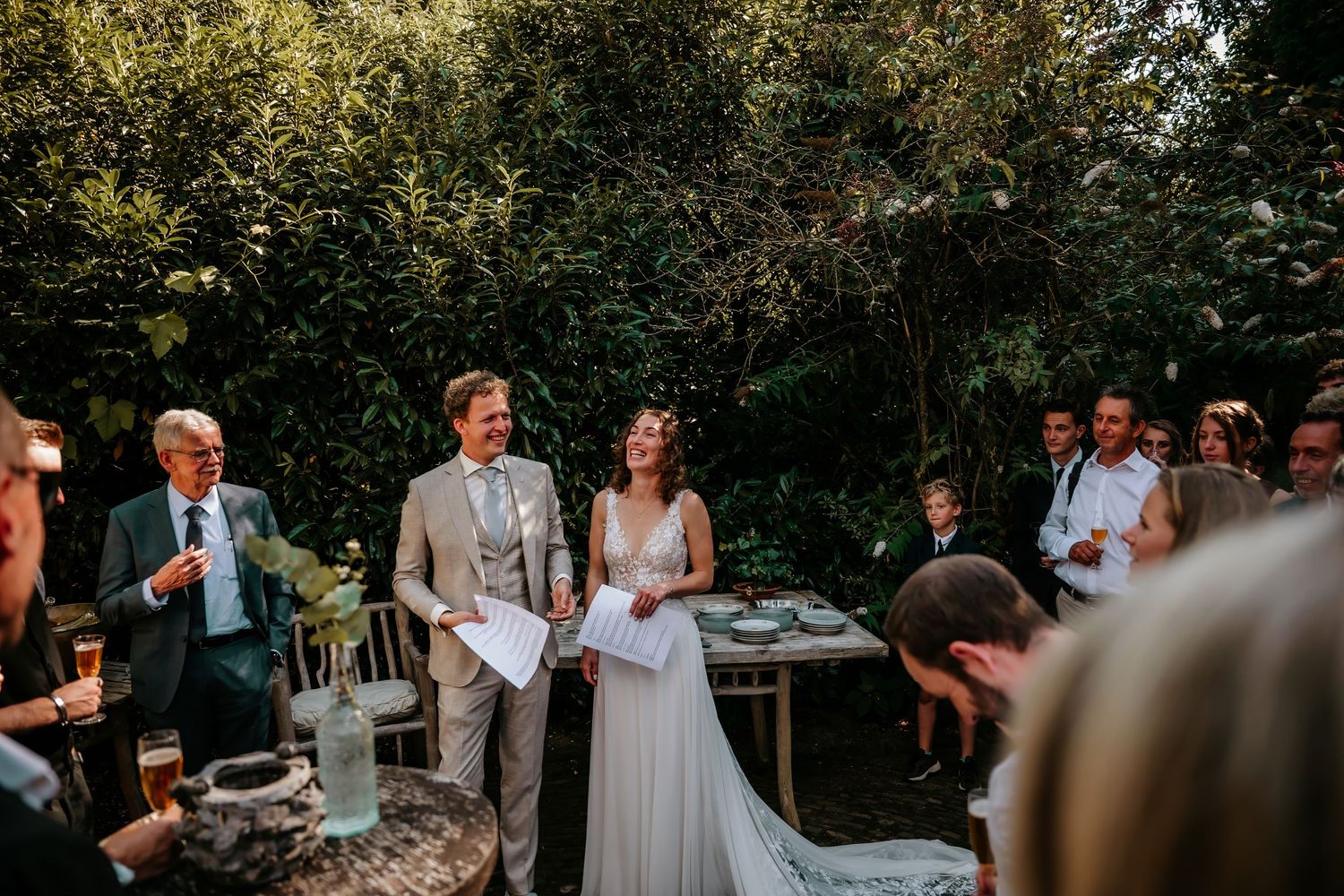 An outdoor wedding ceremony taking place in a garden setting with natural greenery.