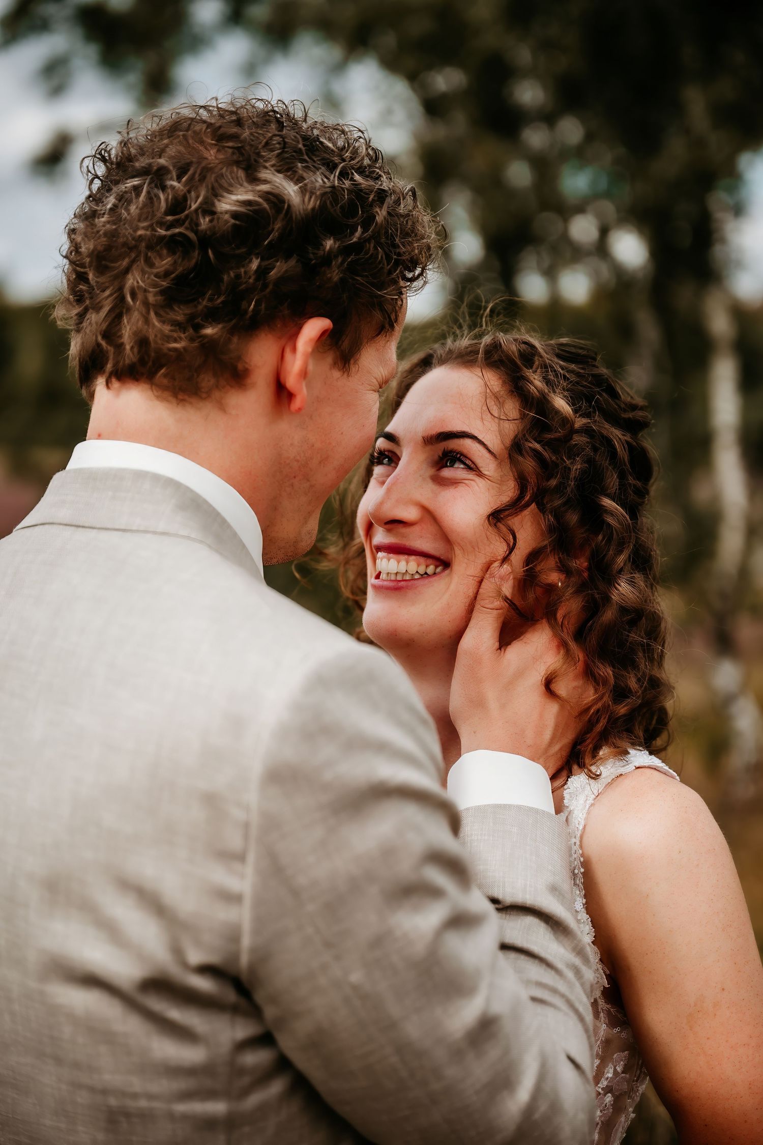 A tender moment between newlyweds with natural outdoor lighting and soft bokeh background.
