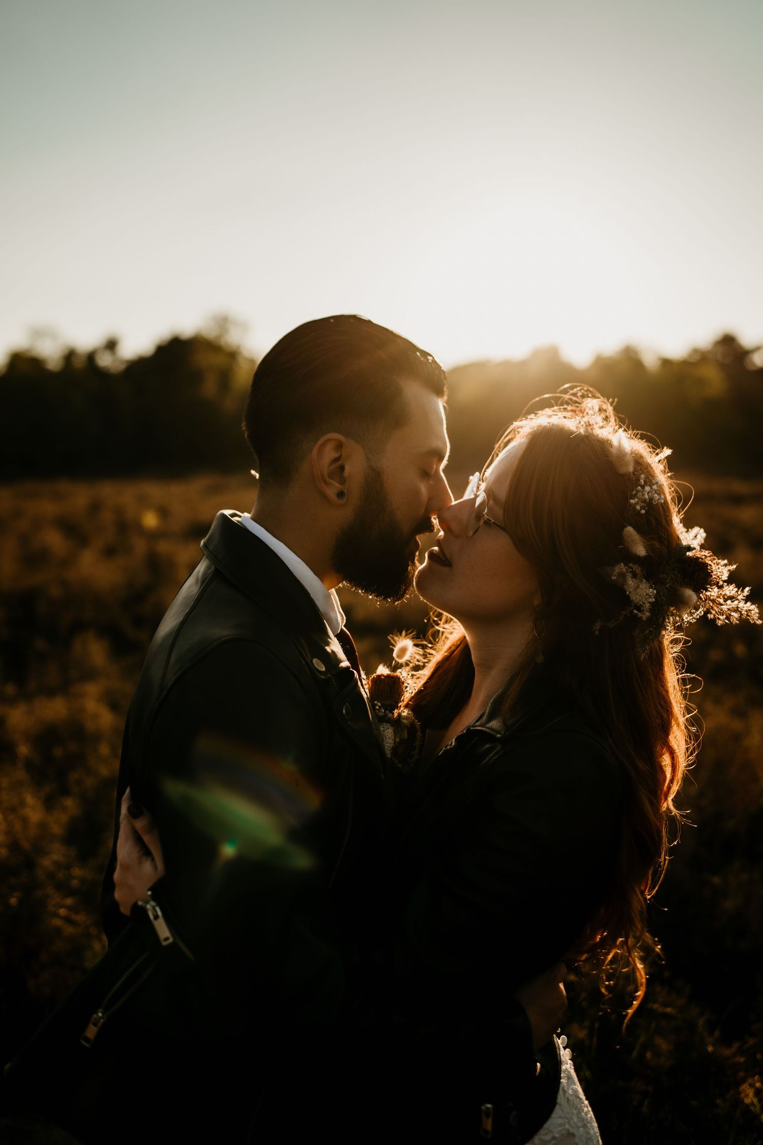 Romantic sunset silhouette of couple embracing in a golden-lit field.