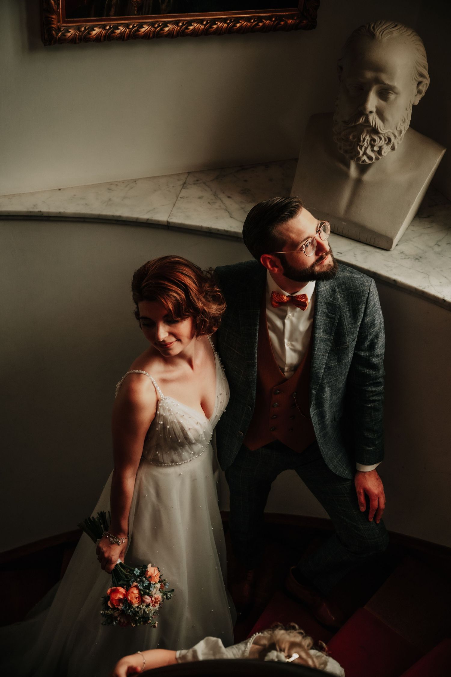 A couple in wedding attire sharing an intimate moment in a dimly lit room.