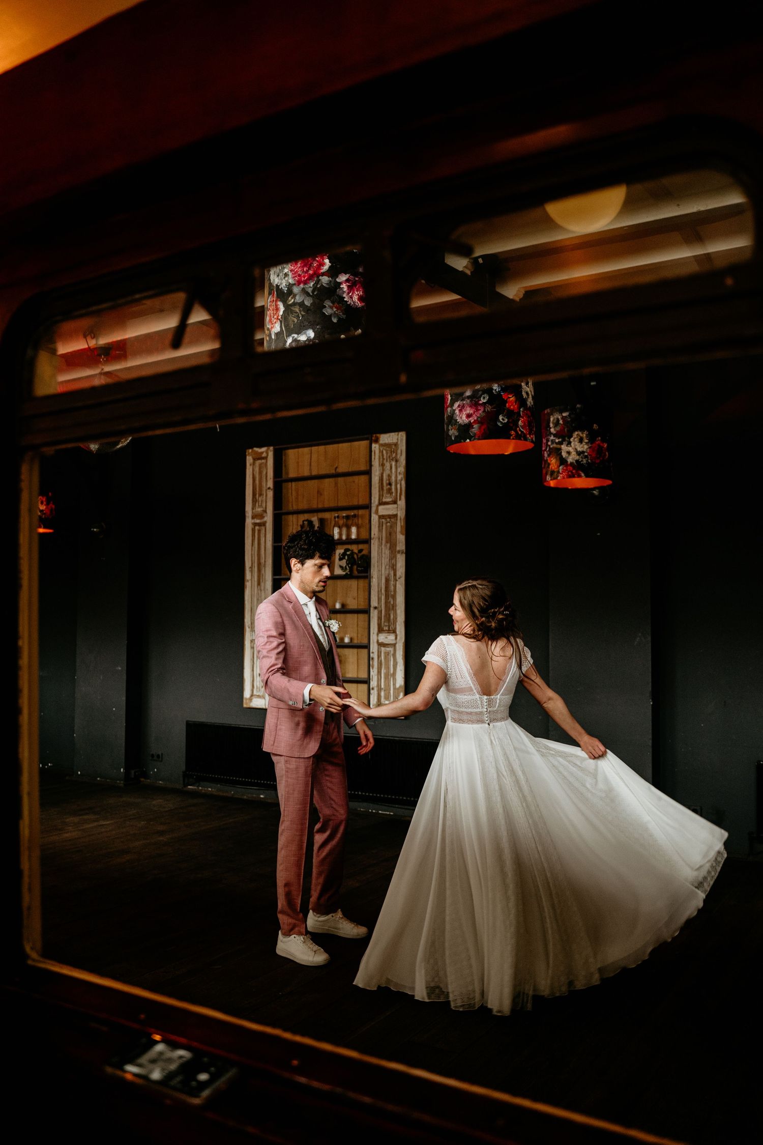 A couple dancing in formal attire inside a vintage venue with dark wood paneling.