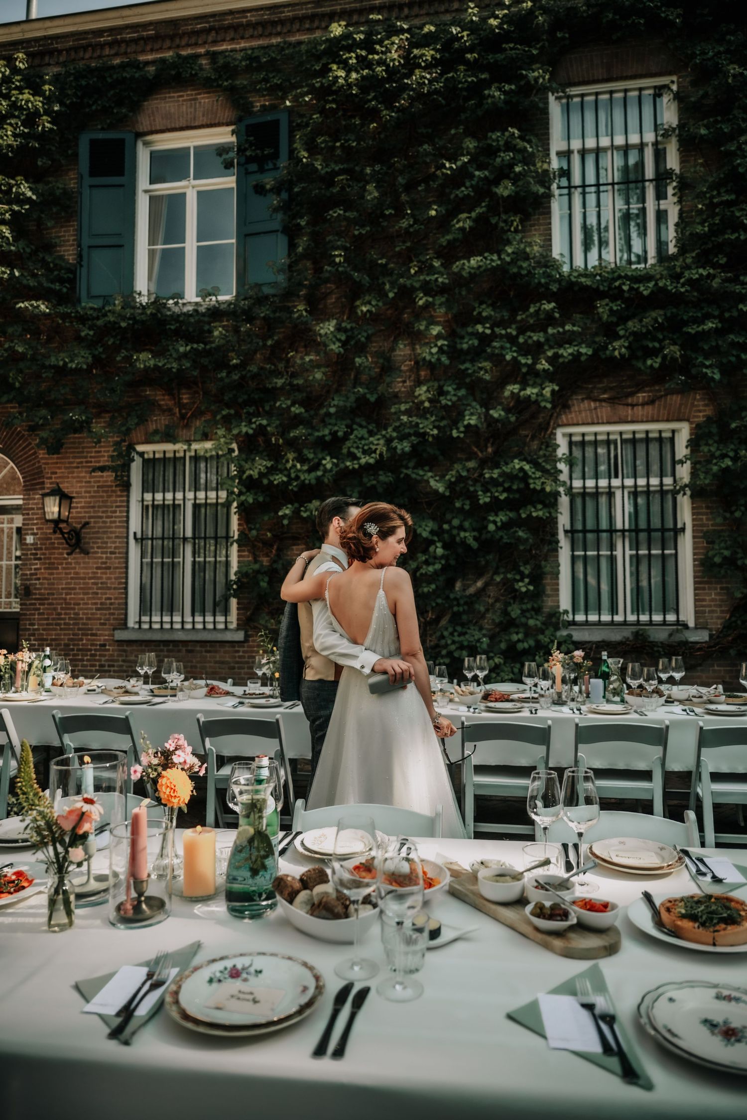 An elegant outdoor wedding reception table setting against an ivy-covered brick building.