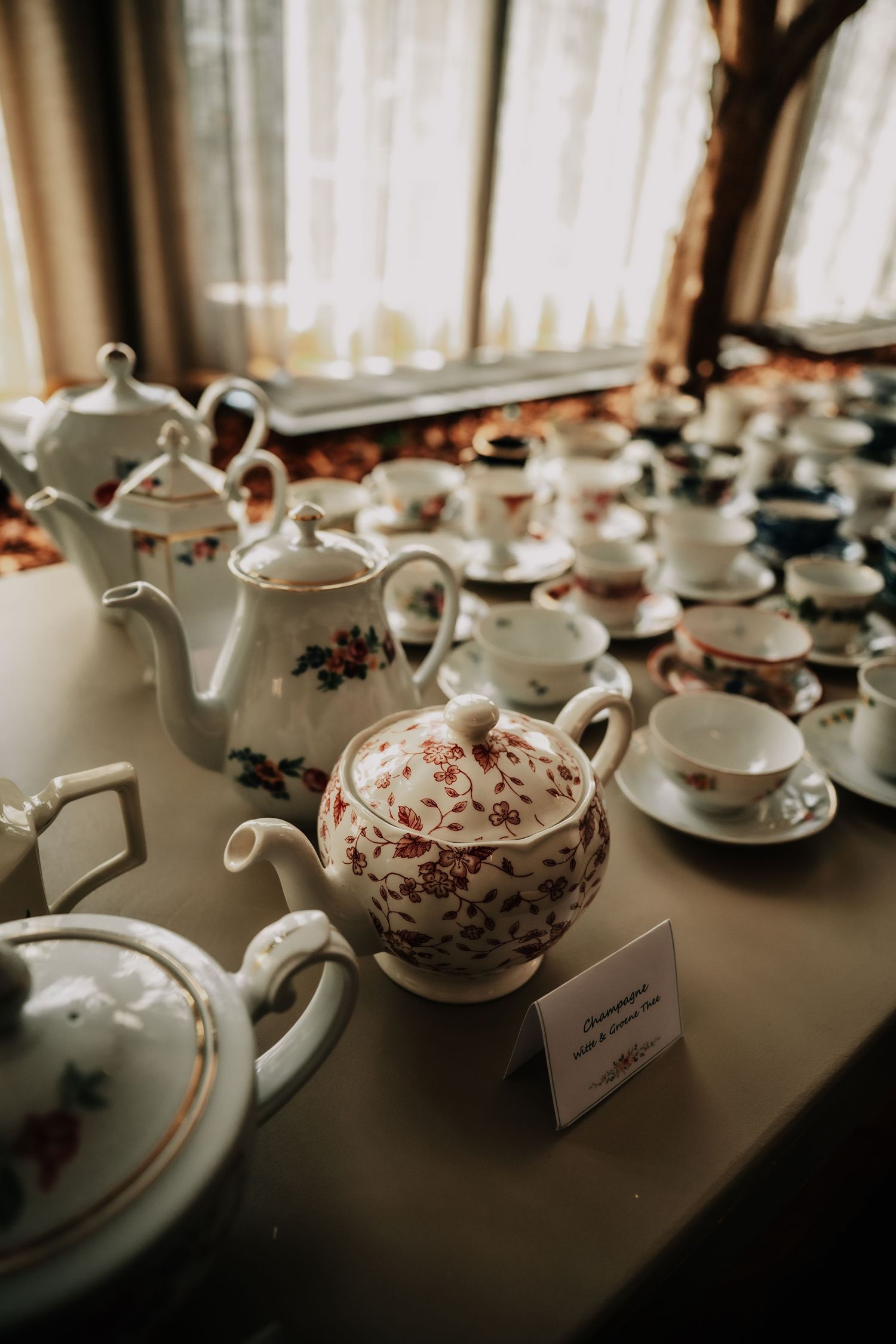 Vintage teapots and cups with floral patterns arranged on a dark table.