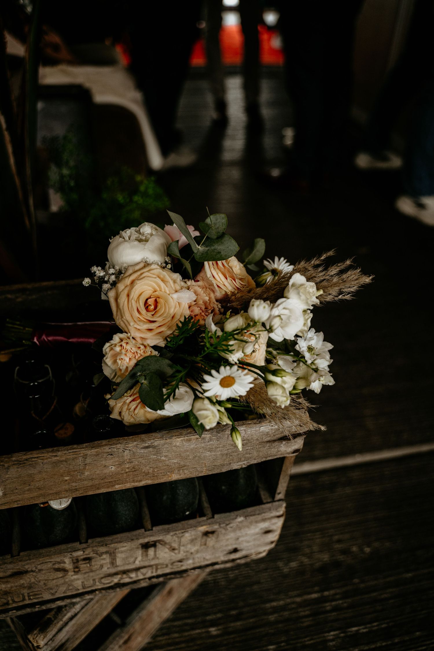 Delicate floral arrangement with roses and daisies on weathered wooden surface.