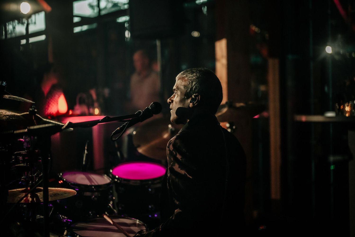 Dark concert stage with dramatic pink and red lighting effects.