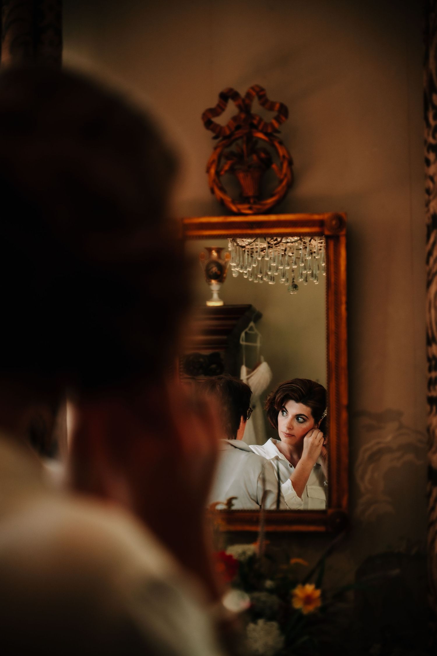 A dramatic reflection in an ornate mirror creates a moody vintage-style portrait in dark tones.