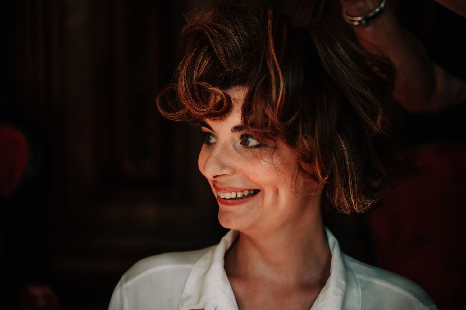 A series of close-up portraits in dark lighting showing expressive smiles and laughter.