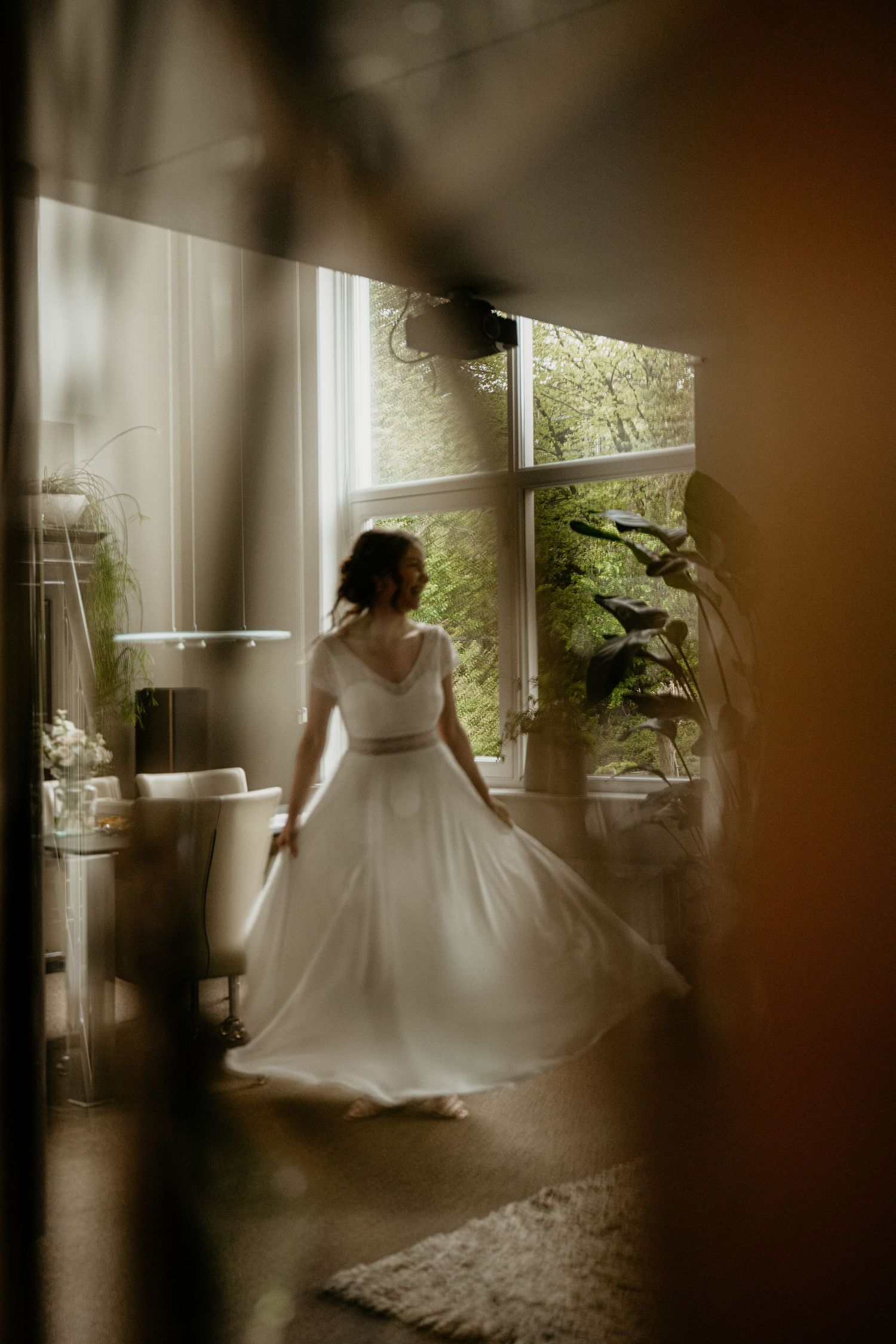 A sequence of romantic wedding dress twirls captured in moody indoor lighting near windows with plants.