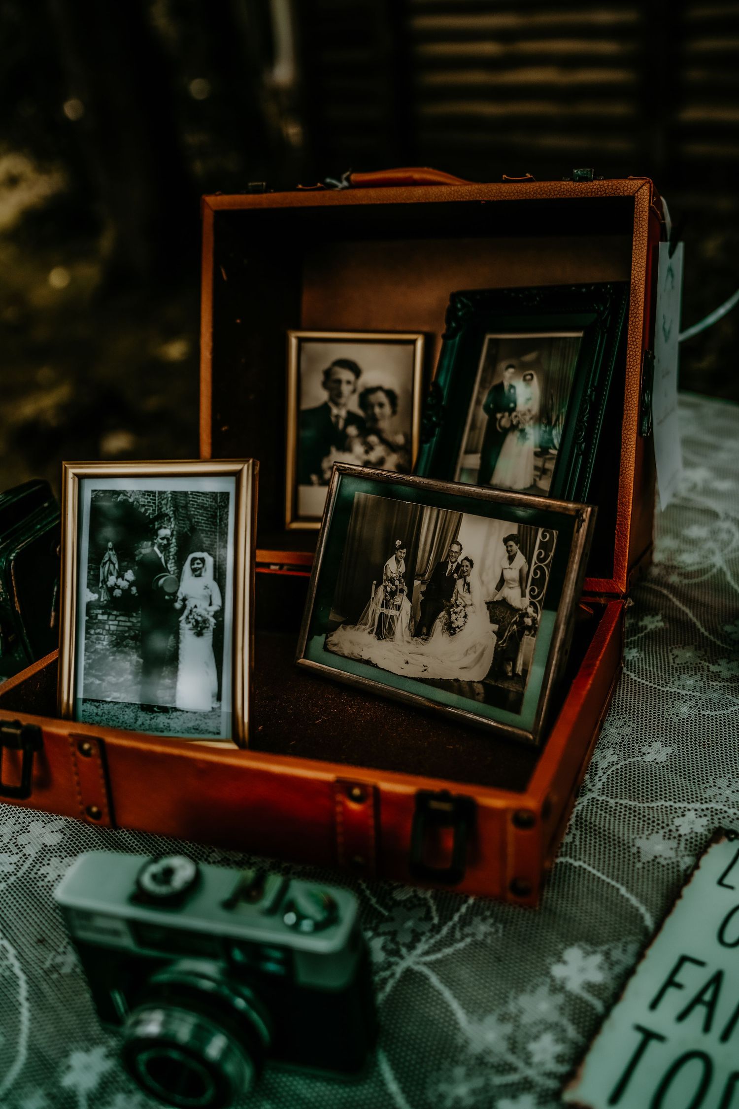 Vintage photographs displayed in an open leather suitcase next to an old camera.