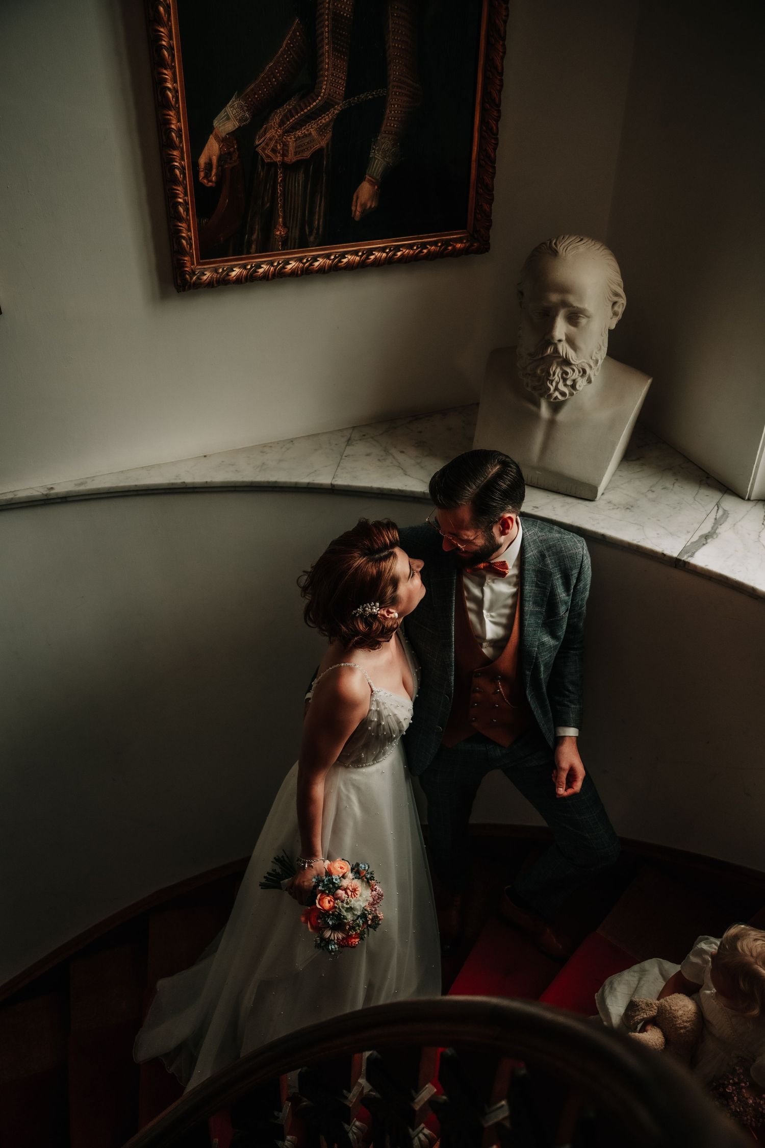 Intimate moment captured in dark atmospheric lighting with ornate frames on wall.