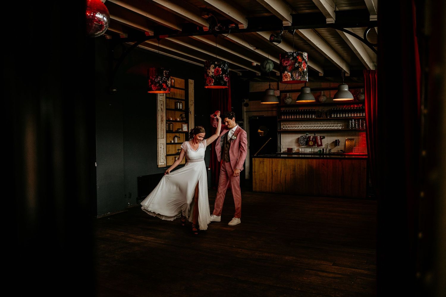 A couple dancing together in a dimly lit rustic venue with wooden beams overhead.
