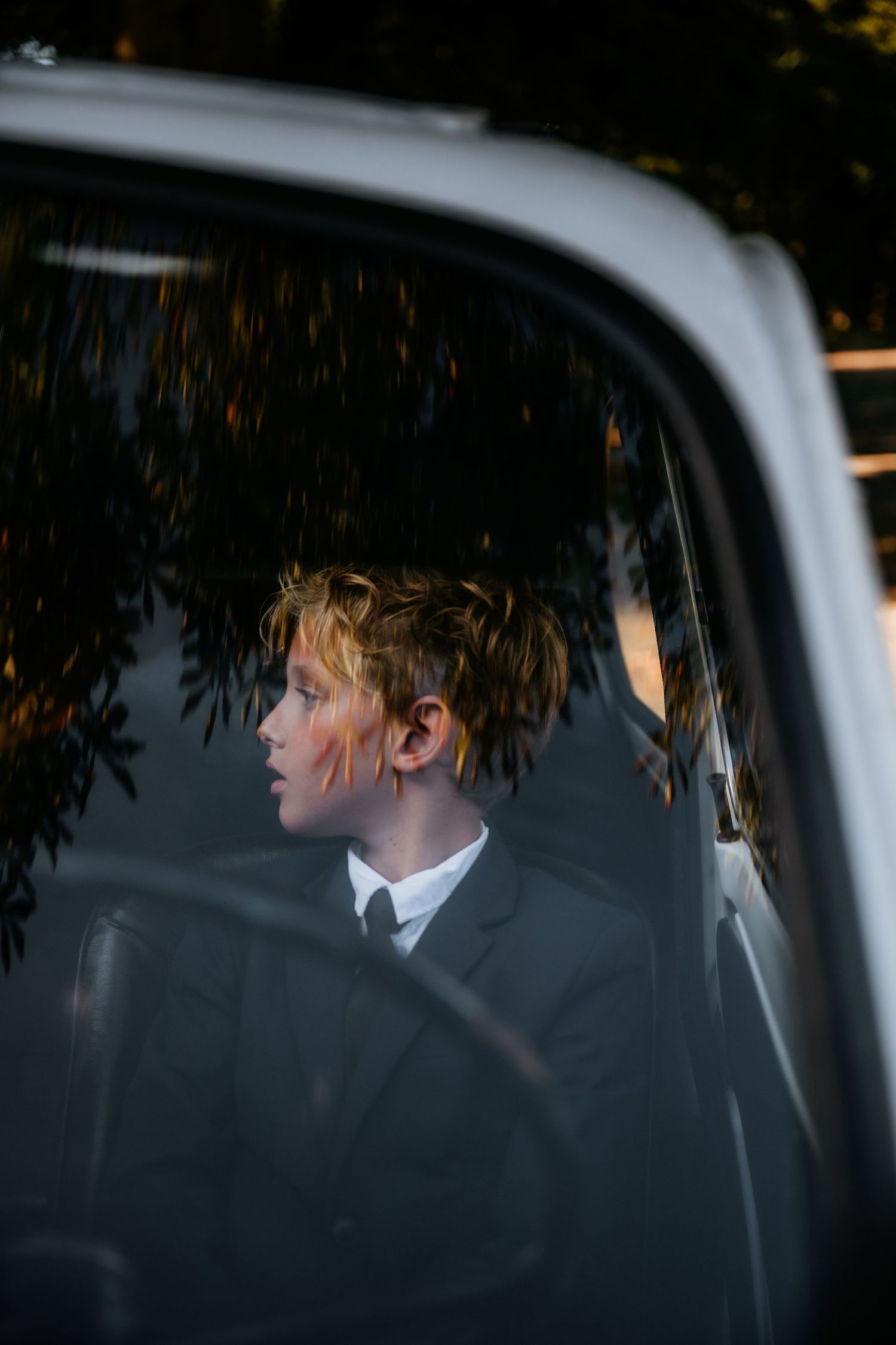 Artistic through-the-window shot of wedding couple in car.