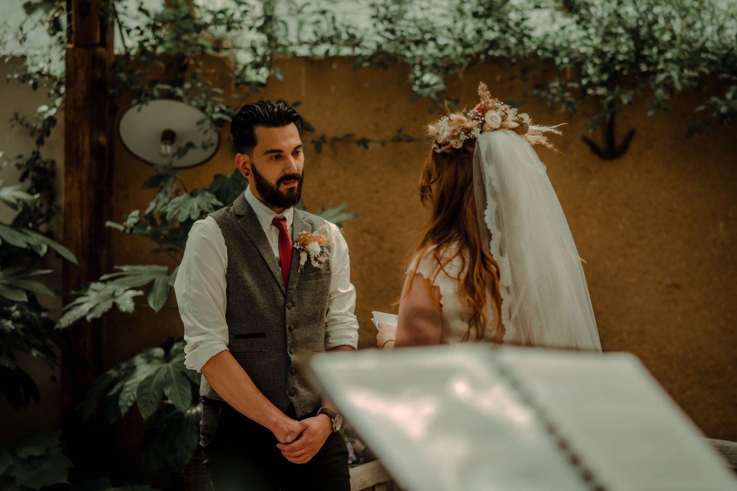 Wedding ceremony in a rustic outdoor venue with natural greenery and sunlight.