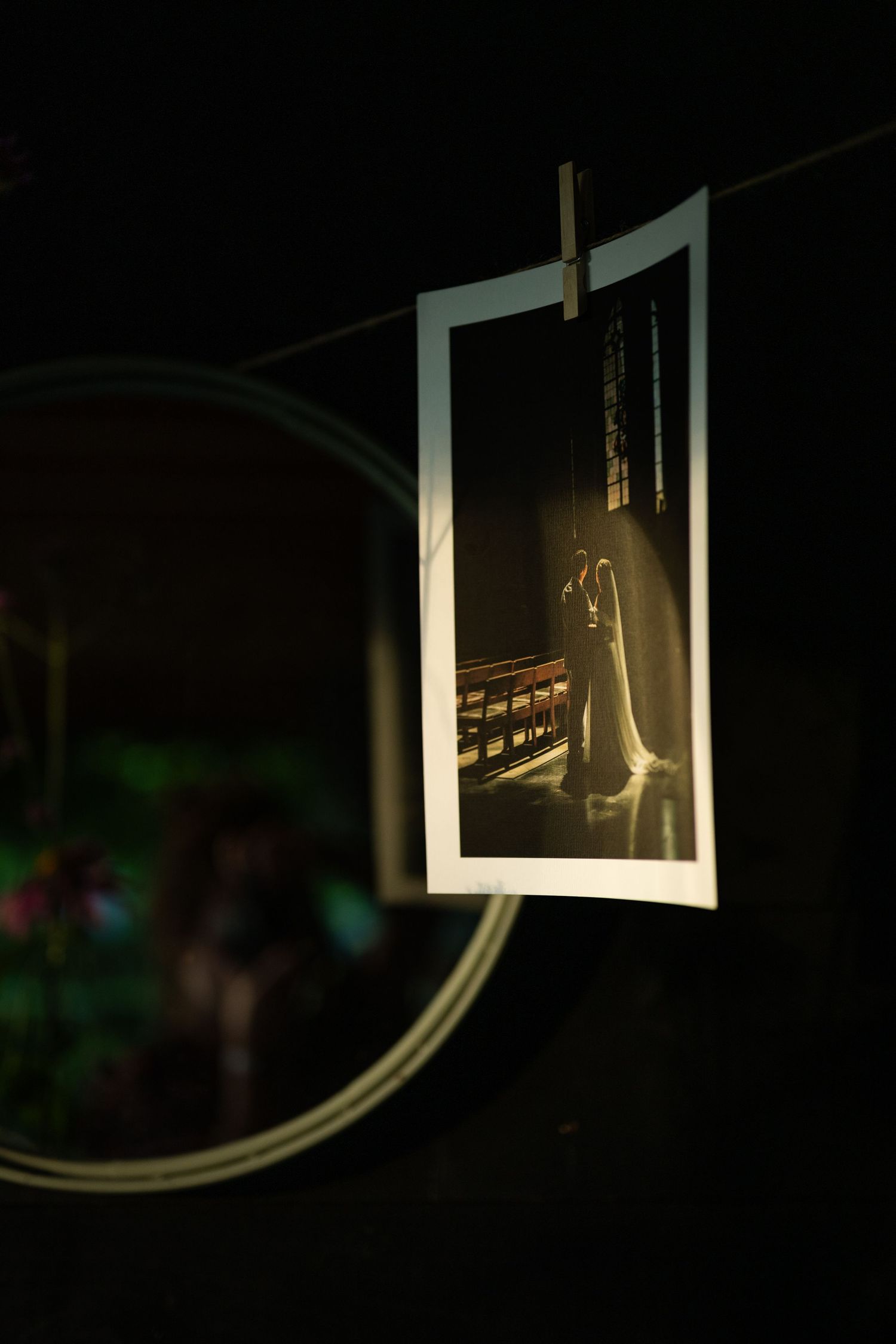 A wedding photo clipped to a string in darkness, showing a bride in a glowing church aisle.